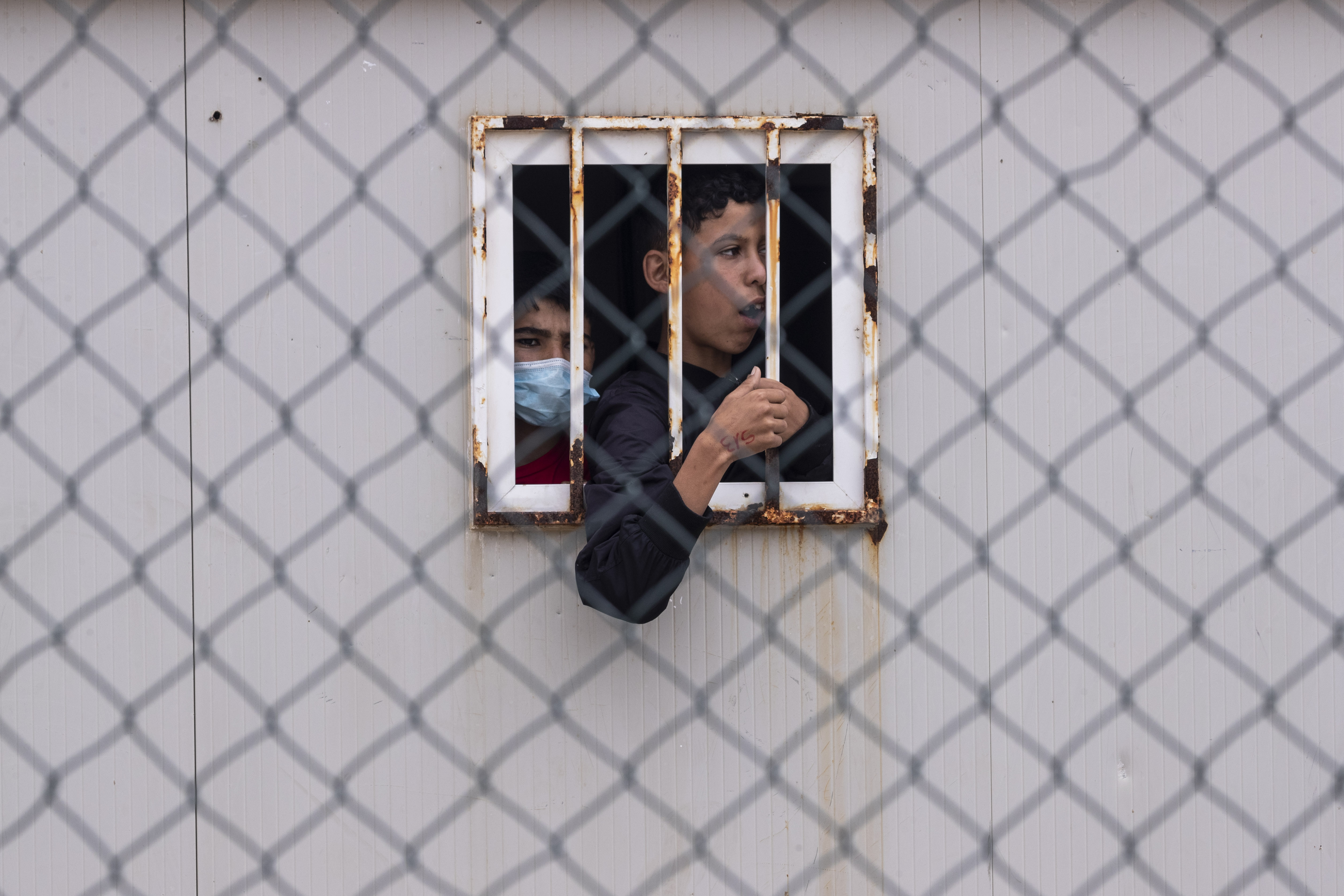 A teenage boy puts his arms out of a small window