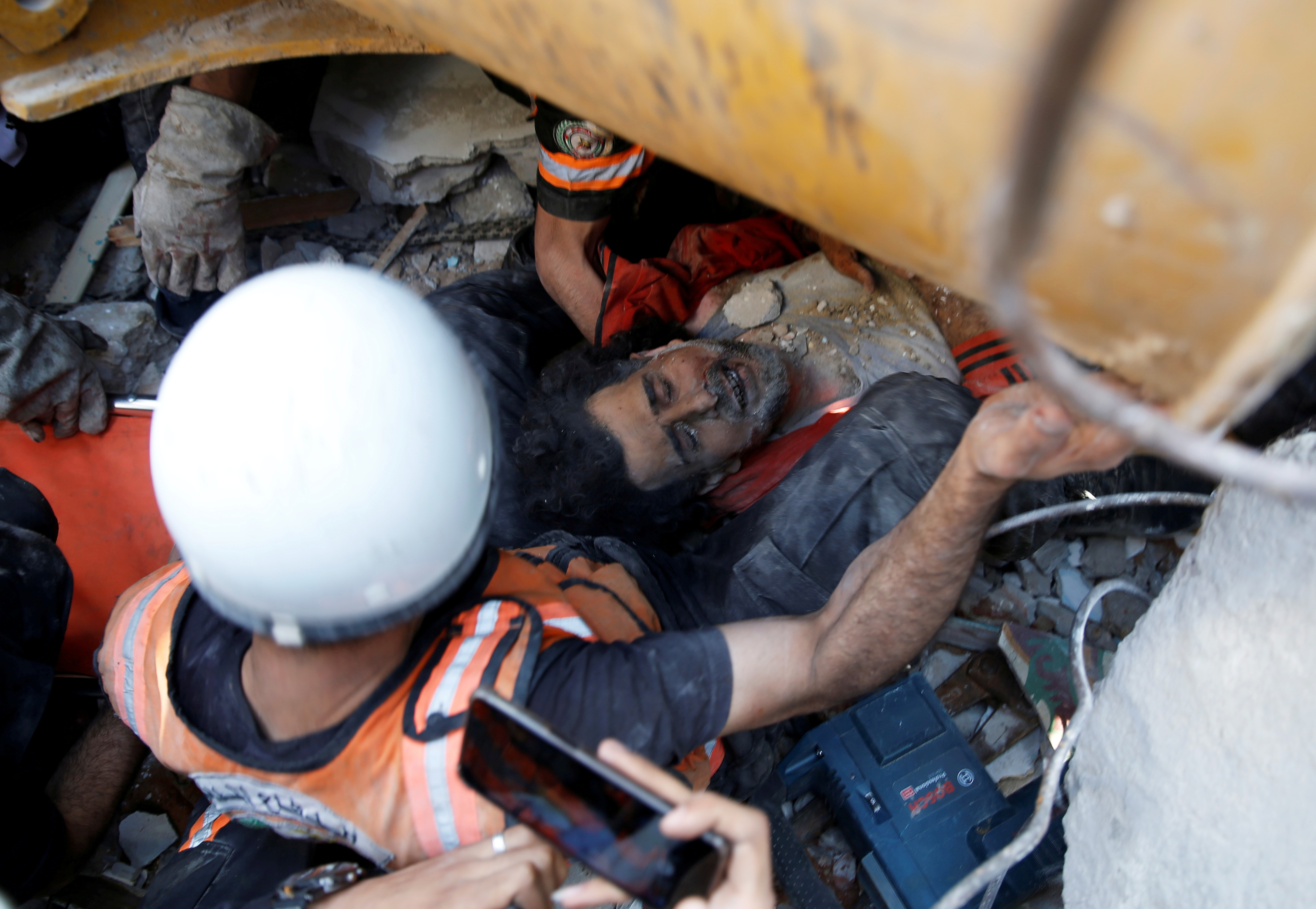 Rescue workers attend to a victim in the rubble at the site of Israeli air strikes in Gaza City on Sunday [Mohammed Salem/Reuters]