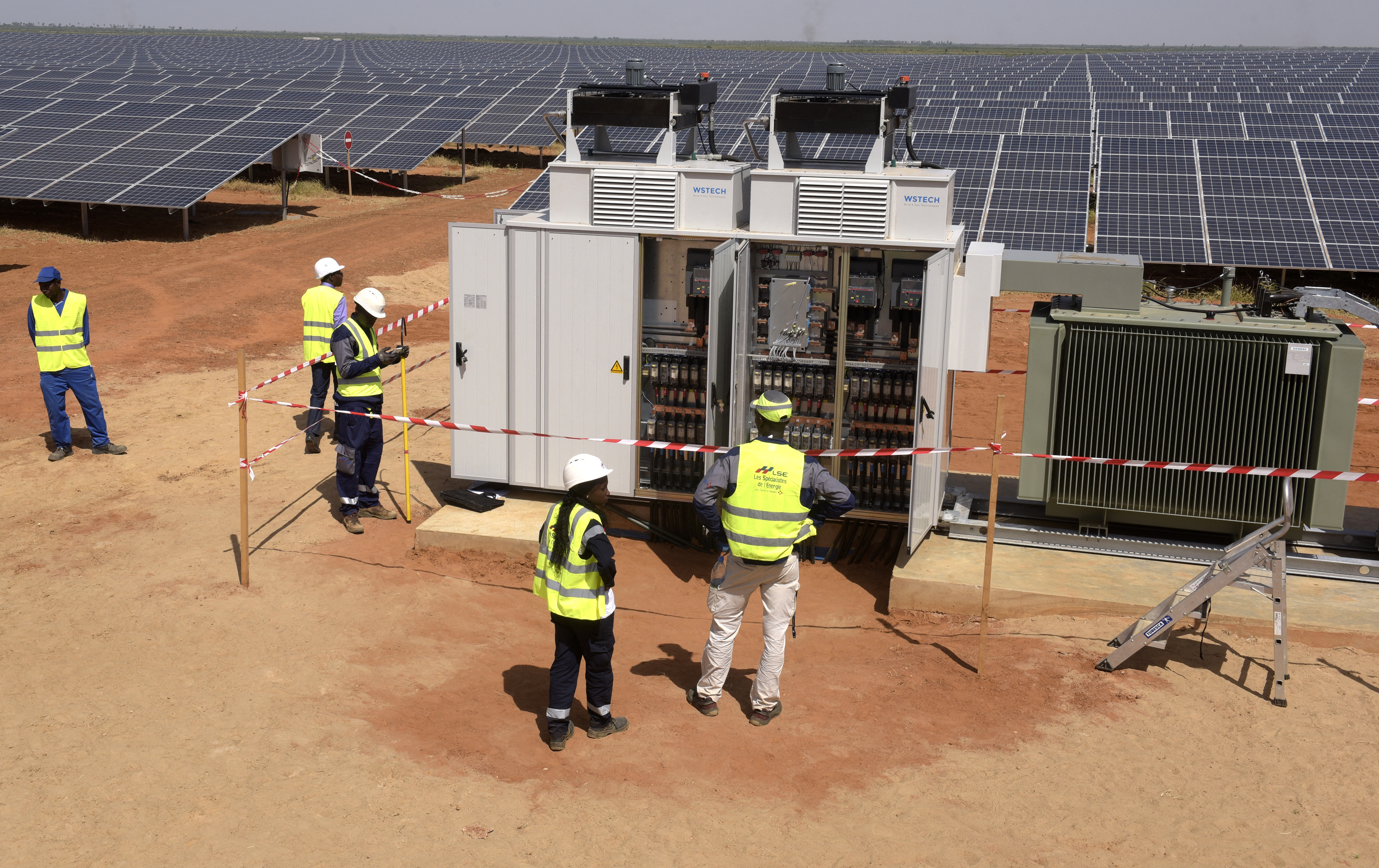 Technicians operate electrical cabinets on October 22, 2016 during the opening ceremony of a new photovoltaic energy production site in Bokhol, Senegal [File: AFP/Seyllou]