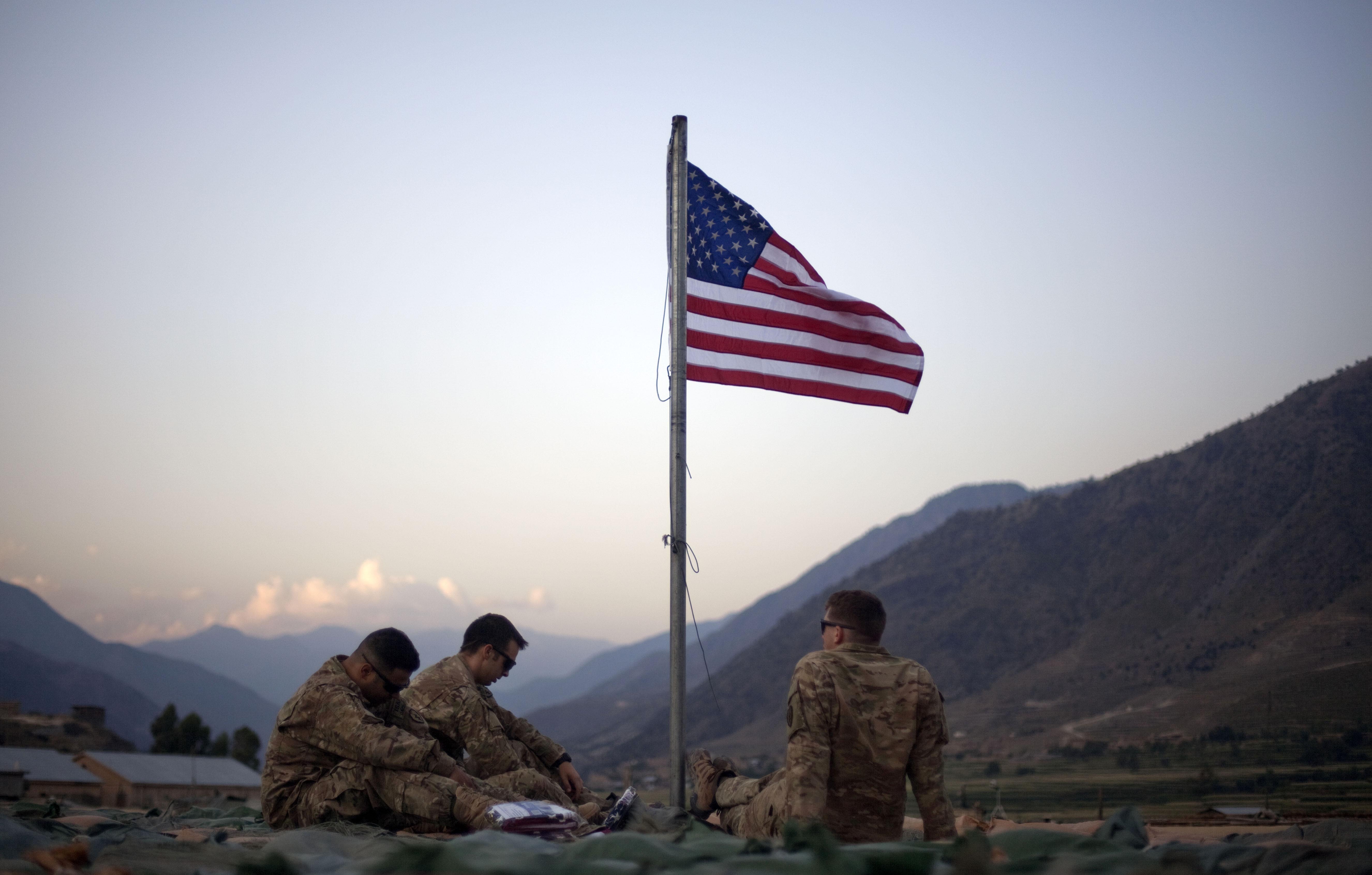 In this file photo from September 11, 2011, US soldiers sit beneath an American flag just raised to commemorate the tenth anniversary of the 9/11 attacks at Forward Operating Base Bostick in Kunar province, Afghanistan
