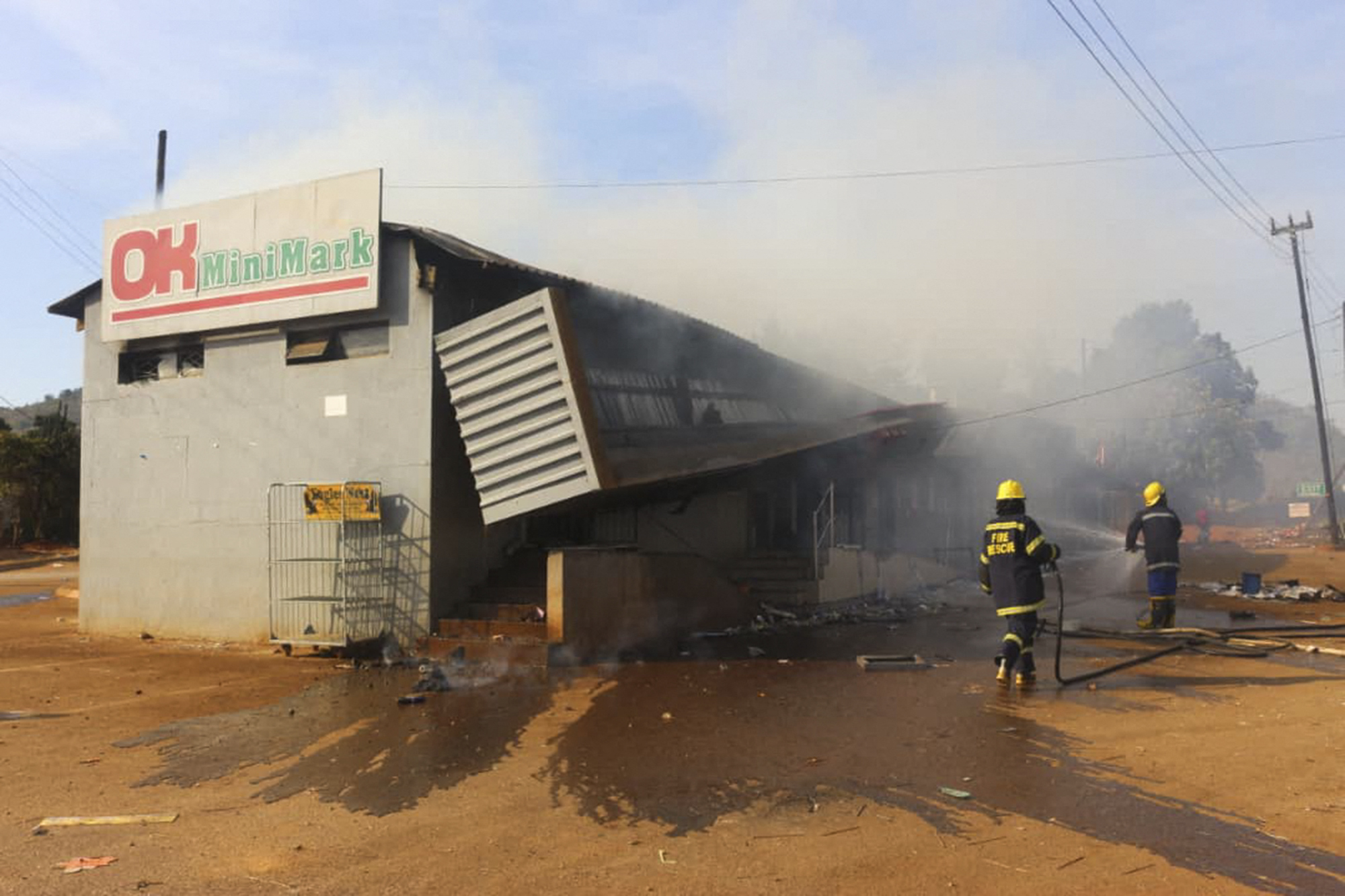 Firefighters extinguish a fire at a supermarket in Manzini. Demonstrations escalated in Eswatini this week as protesters took to the streets demanding immediate political reforms [AFP]