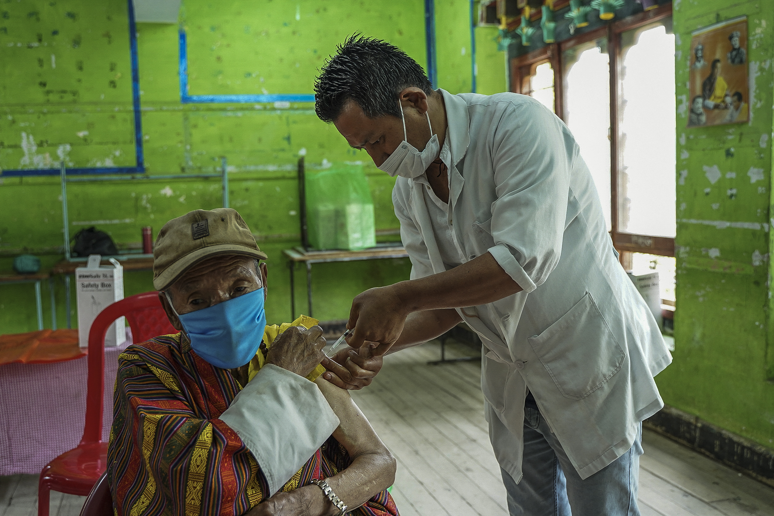 A health worker inoculates an elderly man with the jab of the COVID-19 vaccine at a vaccination centre in Thimphu [Upasana Dahal/AFP]