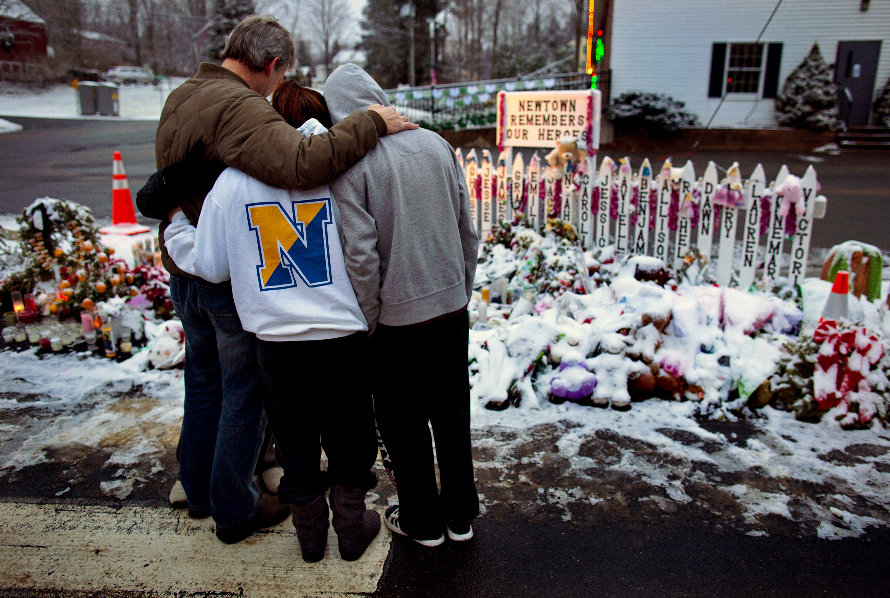 Mourners embrace near memorials by the Sandy Hook firehouse in Newtown, Connecticut