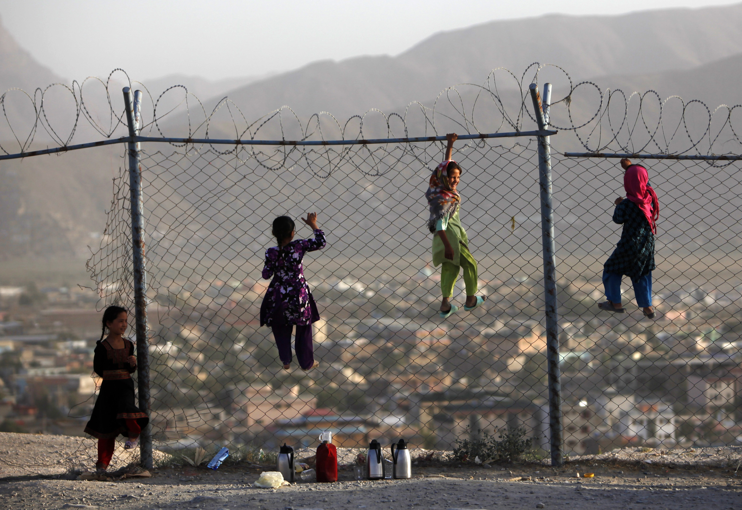 Afghan children climb onto a fence while playing, as they sell tea in Kabul on September 4, 2013 [File: Reuters/Mohammad Ismail]