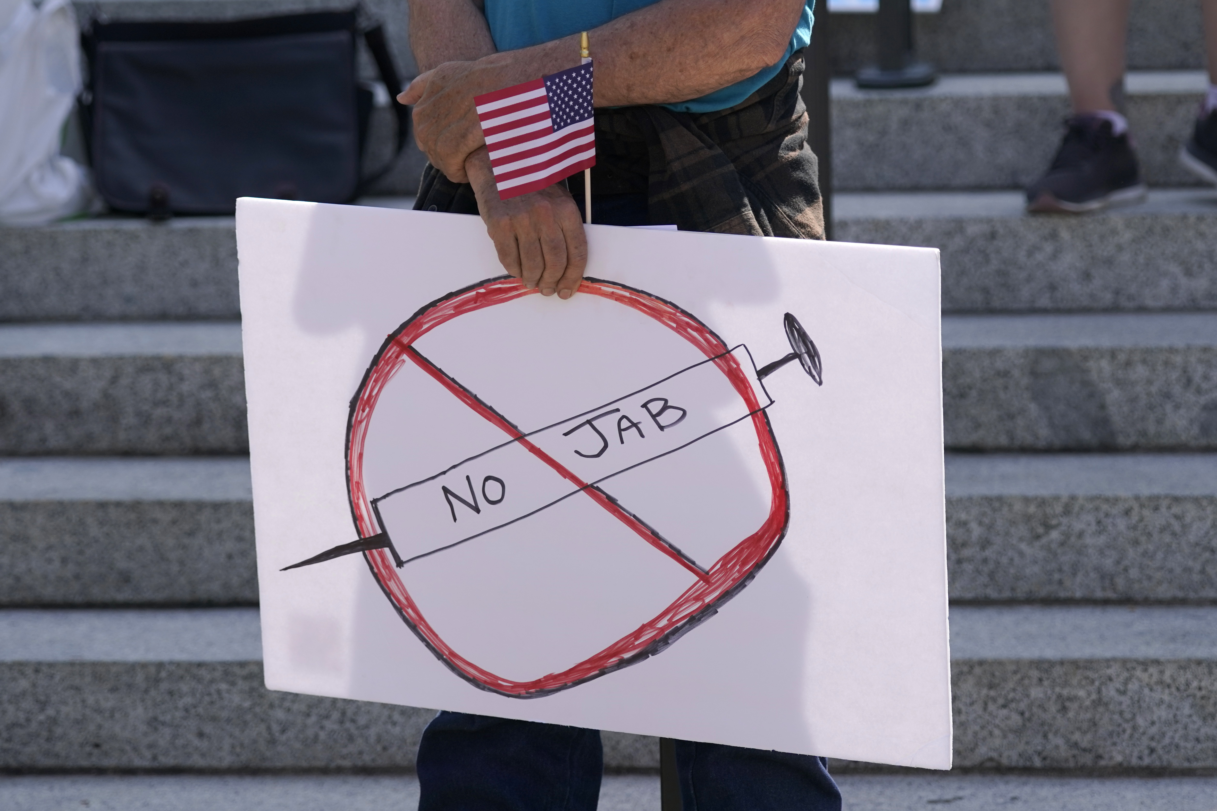 A protester holds a sign that reads ‘No Jab’ at a demonstration opposing mask and COVID-19 vaccine mandates in Olympia, Washington, where the state expanded its vaccine mandate to include all public, charter and private school teachers and staff, as well as those working at the state’s colleges and universities