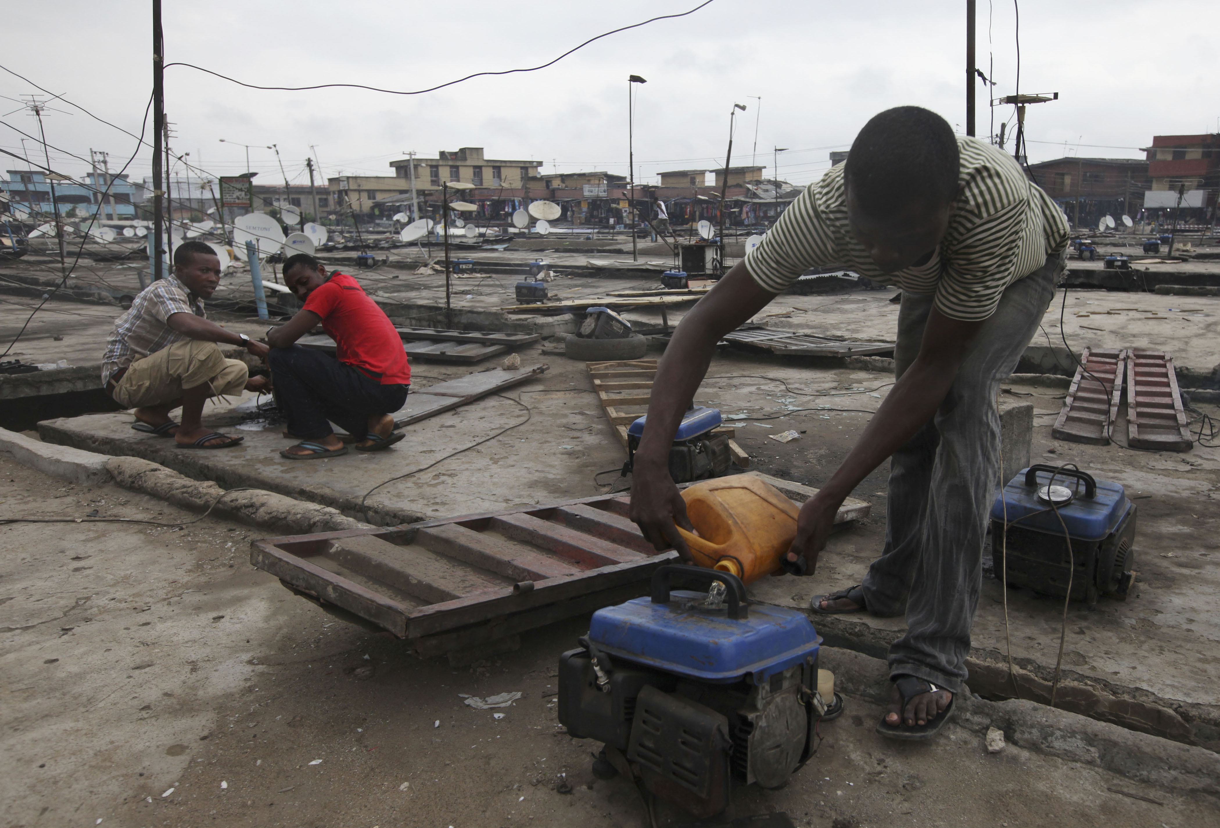 In this photo, a man refuels a small generator on a store rooftop at Oshodi Market in Lagos, Nigeria.