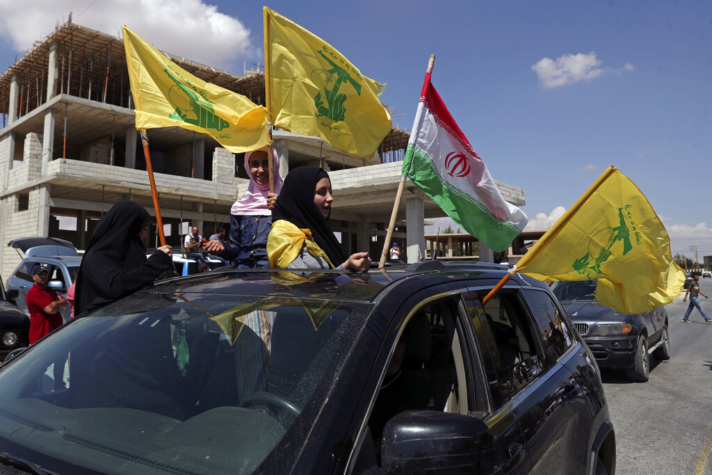 Hezbollah supporters wave an Iranian and Hezbollah flags from a car