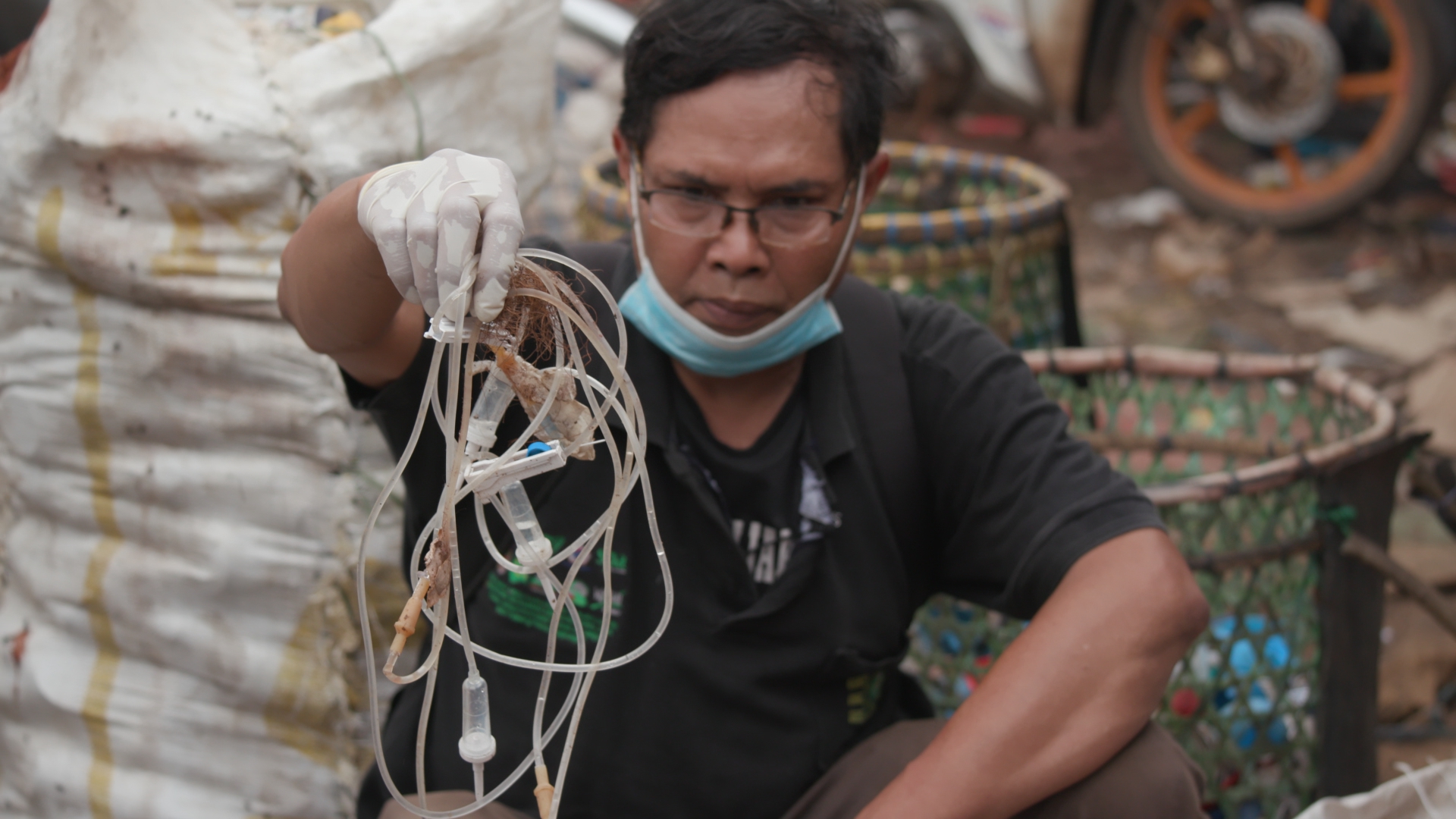 Bagong Suyoto, from the NGO National Waste Coalition, holds up intravenous drip lines with needles still attached, collected by scavengers from landfills on the outskirts of Jakarta, Indonesia [101 East/Al Jazeera]