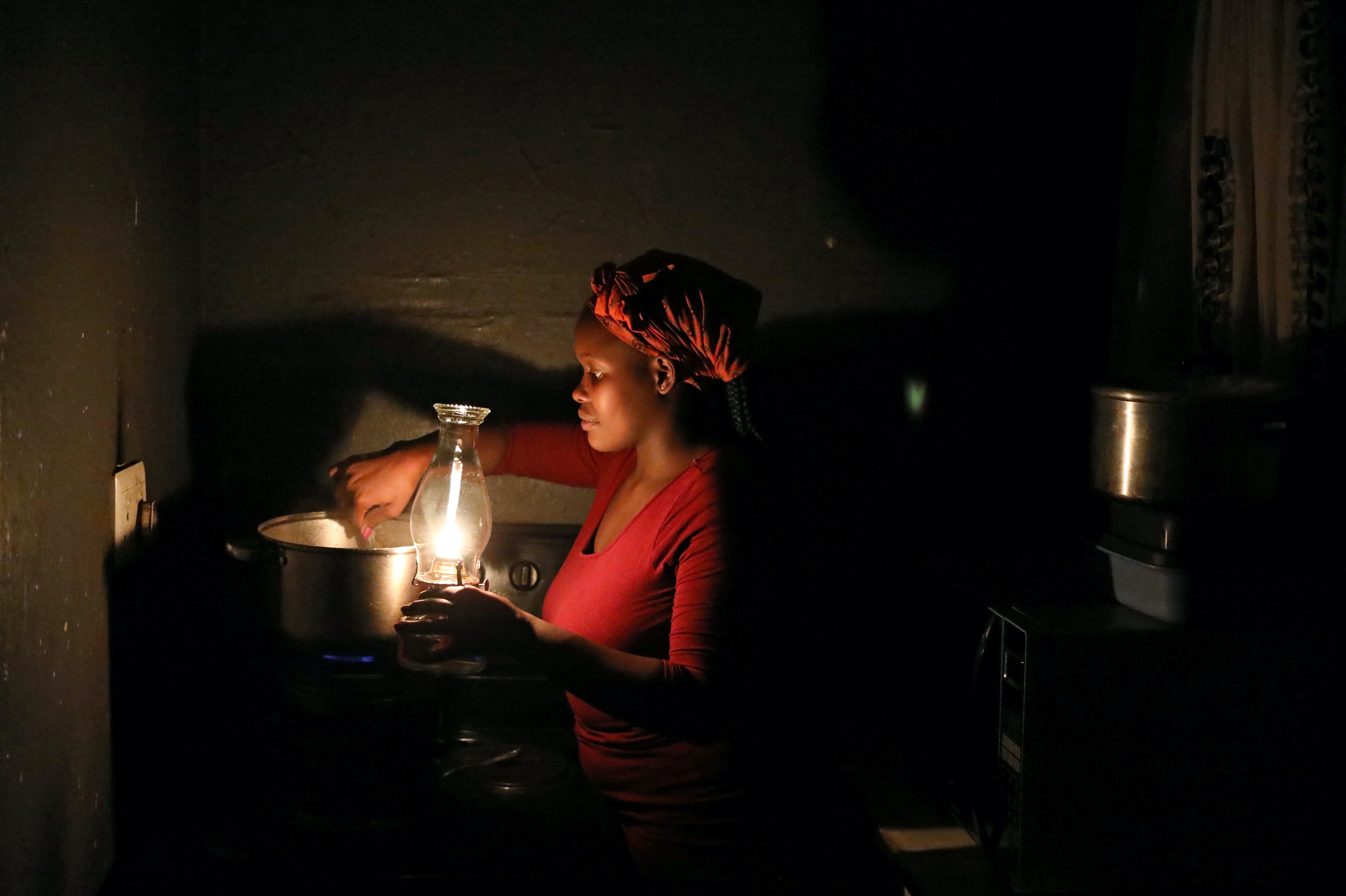 A woman uses paraffin light while cooking during an electricity load-shedding blackout in Soweto, South Africa