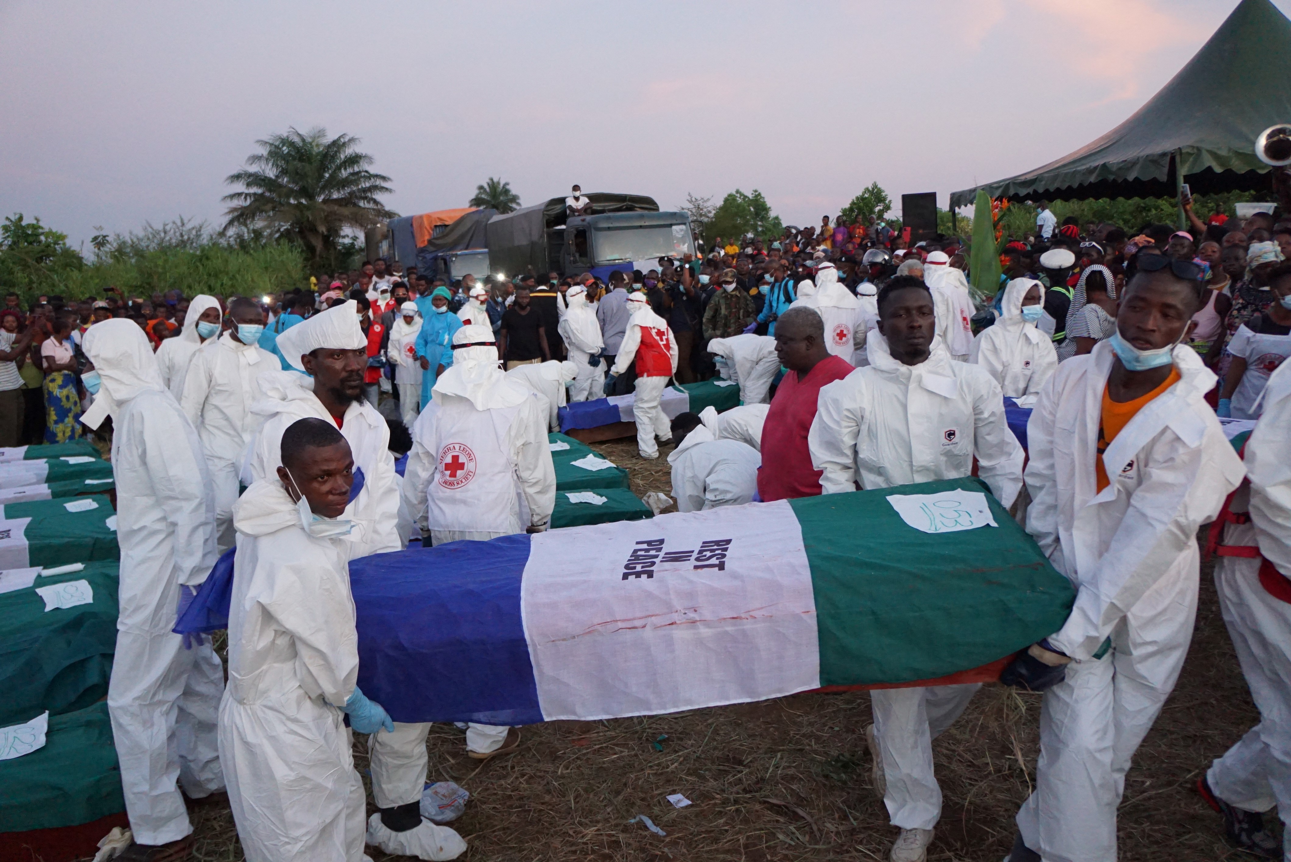 Health workers carry a coffin during the burial of 75 of the victims in Freetown on November 8, 2021, two days after a massive fireball sparked by a fuel tanker explosion killed more than 130 people in Sierra Leone's capital [Saidu Bah/ AFP]