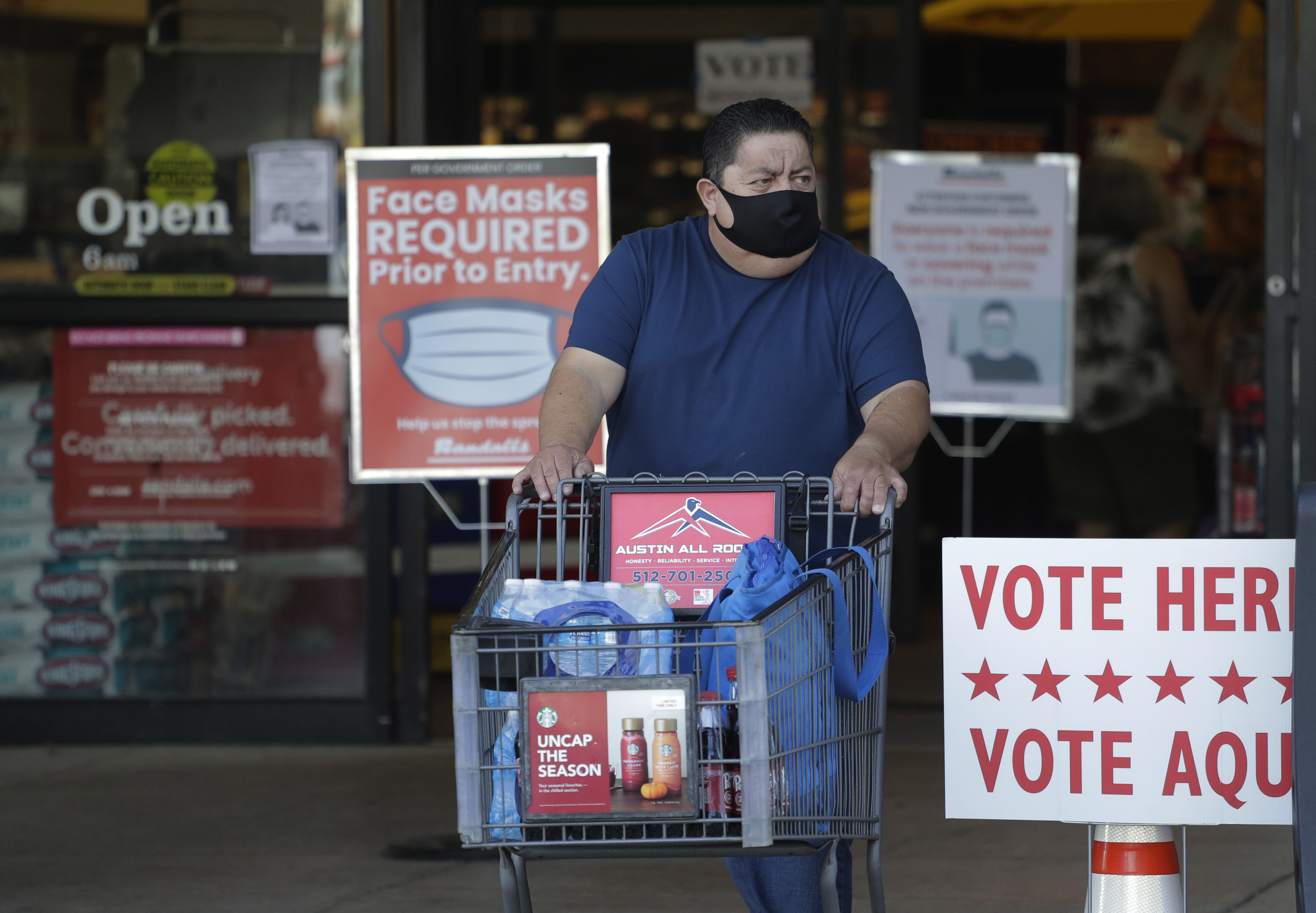 A shopper wearing a mask for protection against COVID-19 leaves a grocery store that is also serving as an early polling site, on Thursday, July 9, 2020, in Austin, Texas