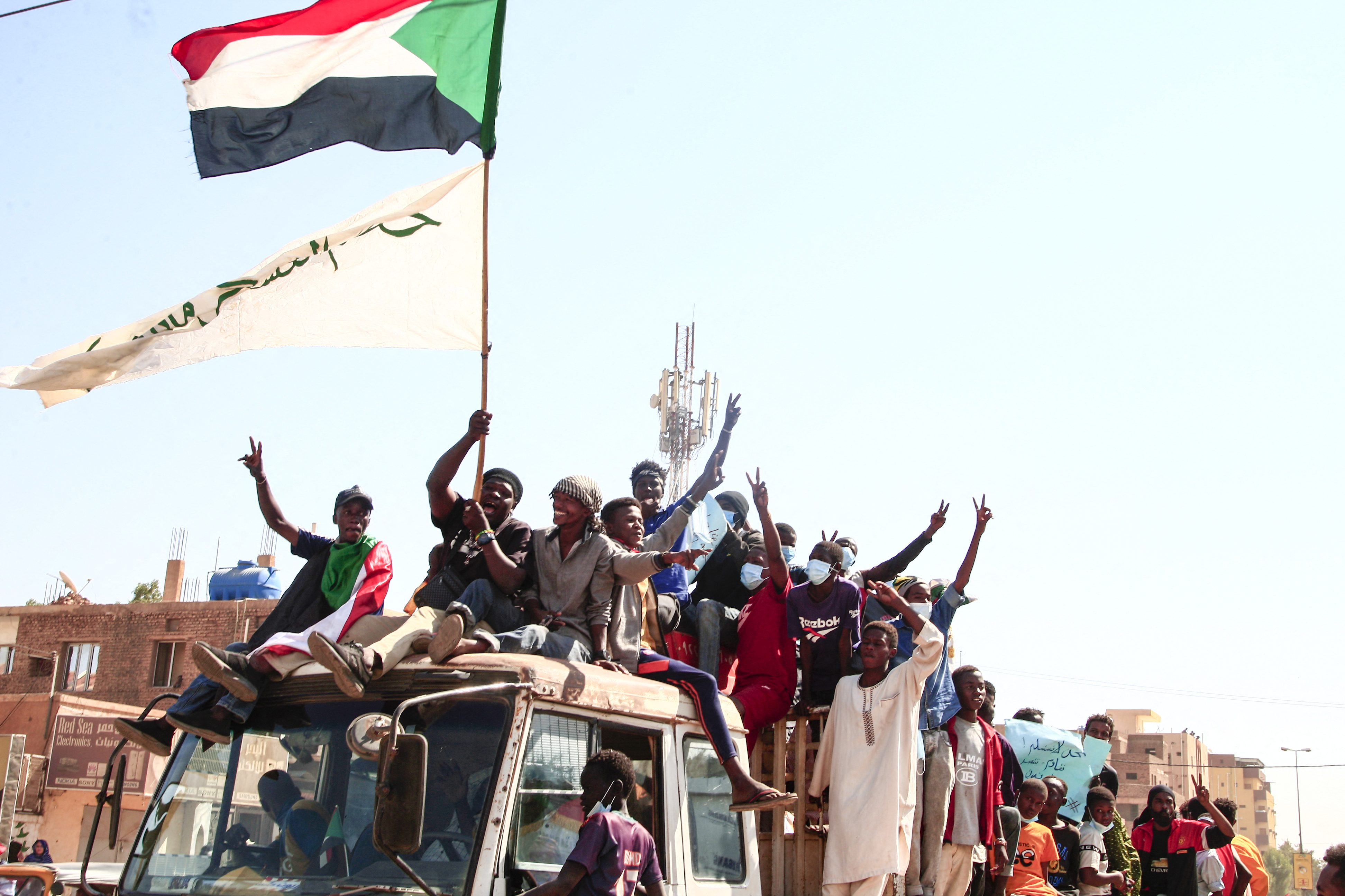 Sudanese youths raise their national flag as they rally against the October 25 coup, followed by a bloody crackdown, in the northern part of the capital Khartoum, on December 19, 2021 [AFP]