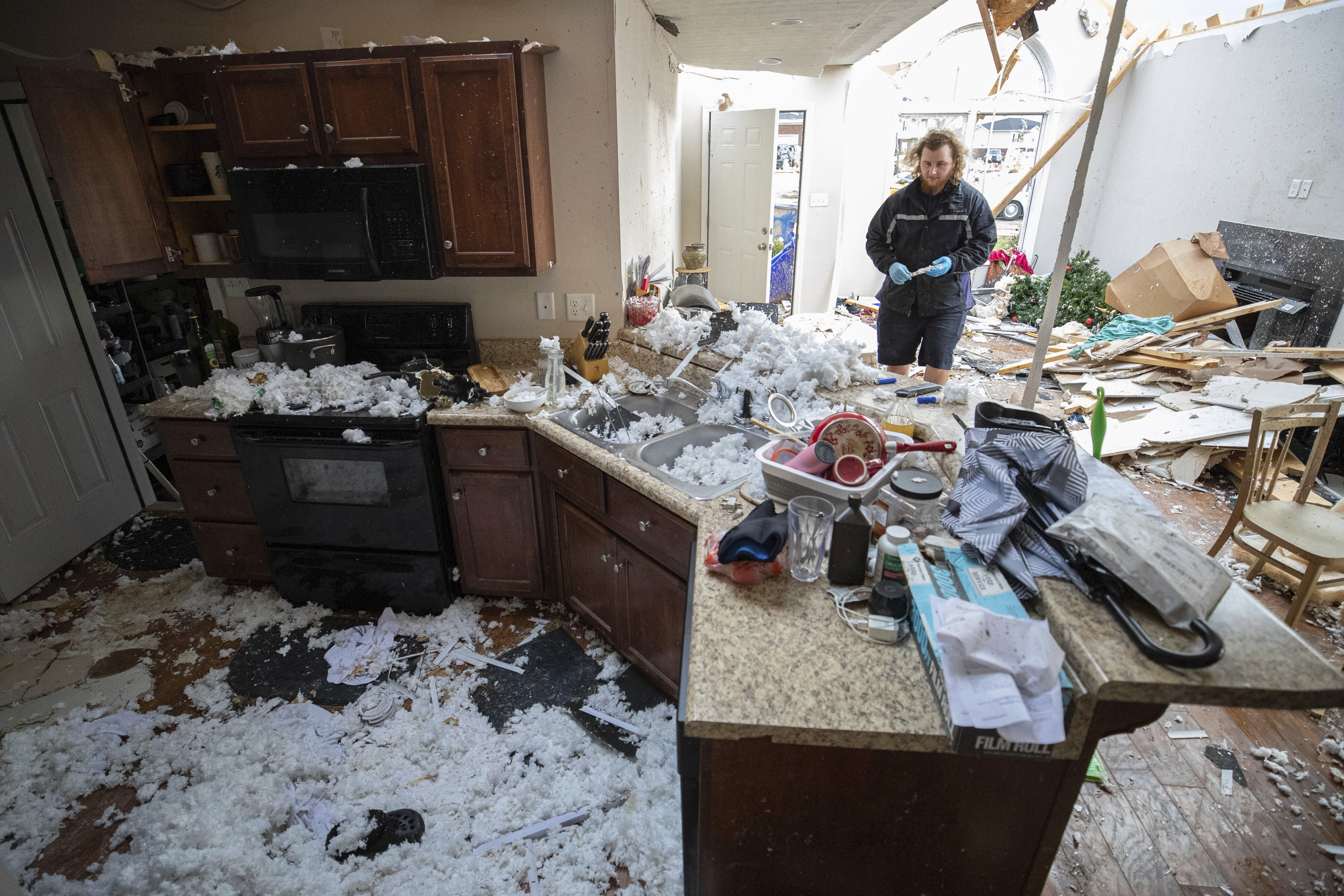 Luke Schockley moves debris from a tornado inside his parent in-law’s house in Bowling Green, Kentucky., Saturday, December 11, 2021