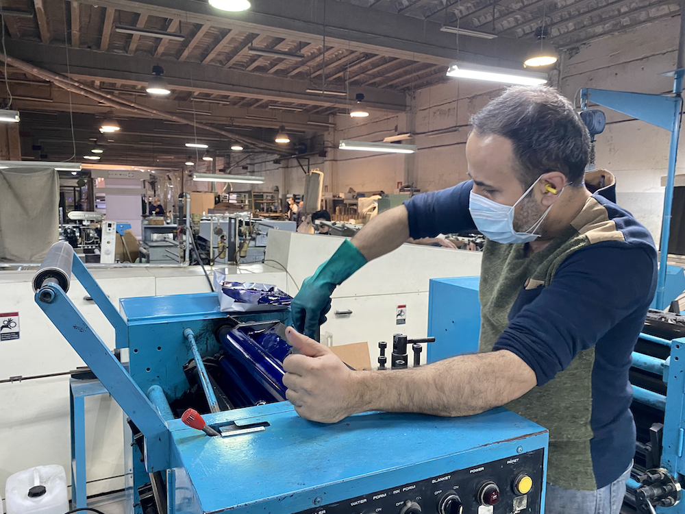 A man works at an industrial machine in a factory.