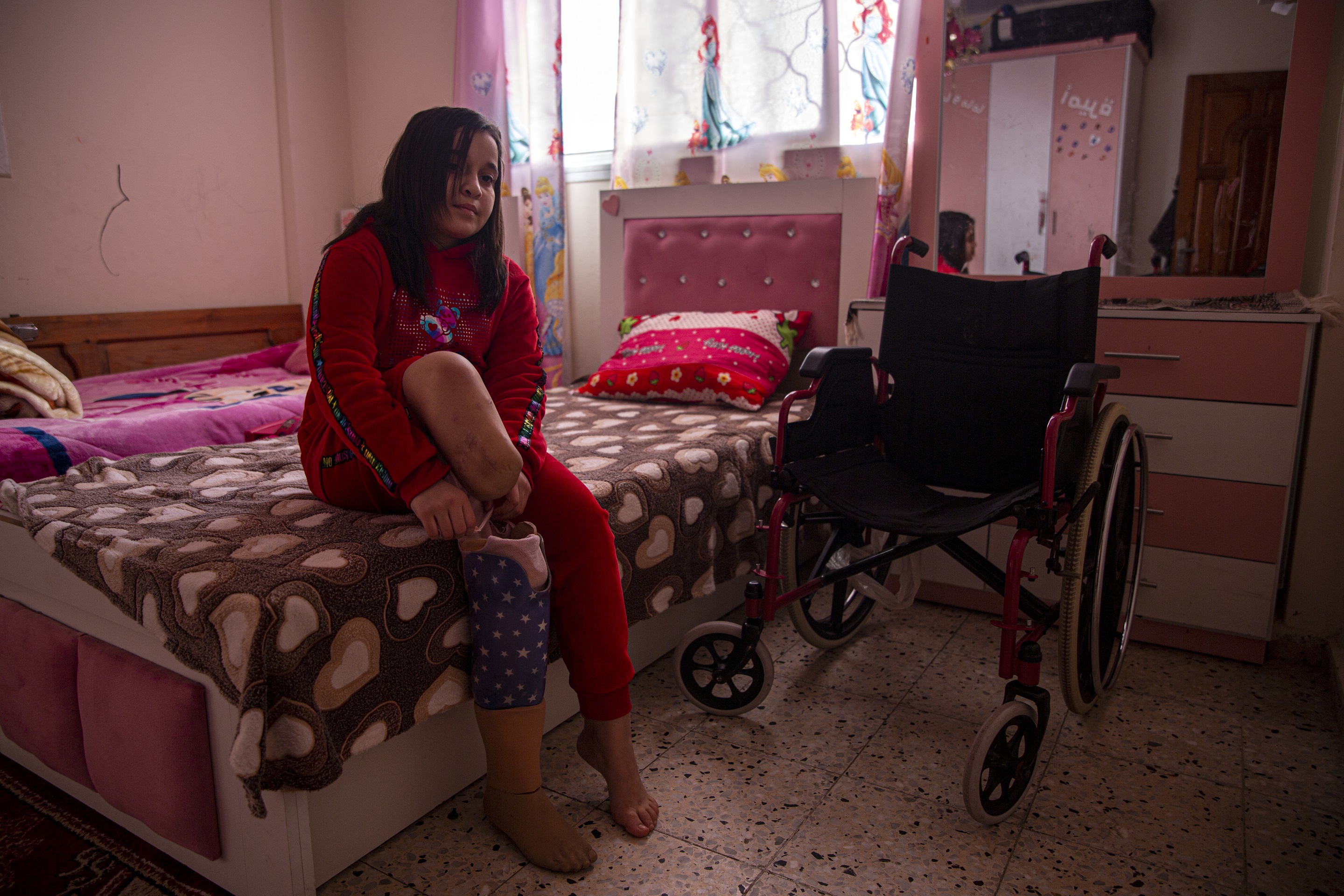 Farah Isleem, 12 years old, wears her prosthetic leg after she lost her leg in an Israeli bombing to their home.
