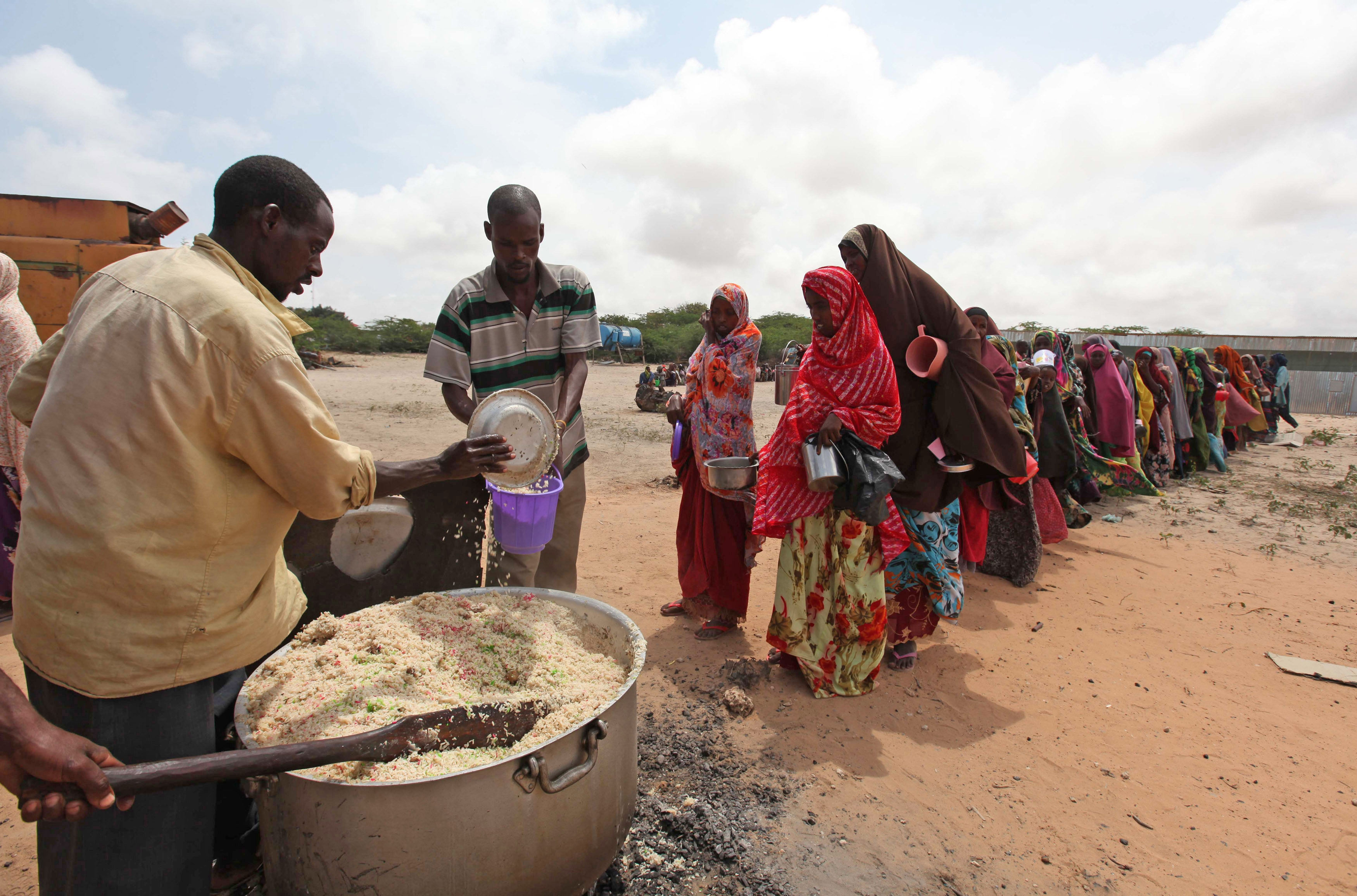 Internally displaced Somali people stand in a queue waiting to be served with cooked food in Hodan district south of capital Mogadishu