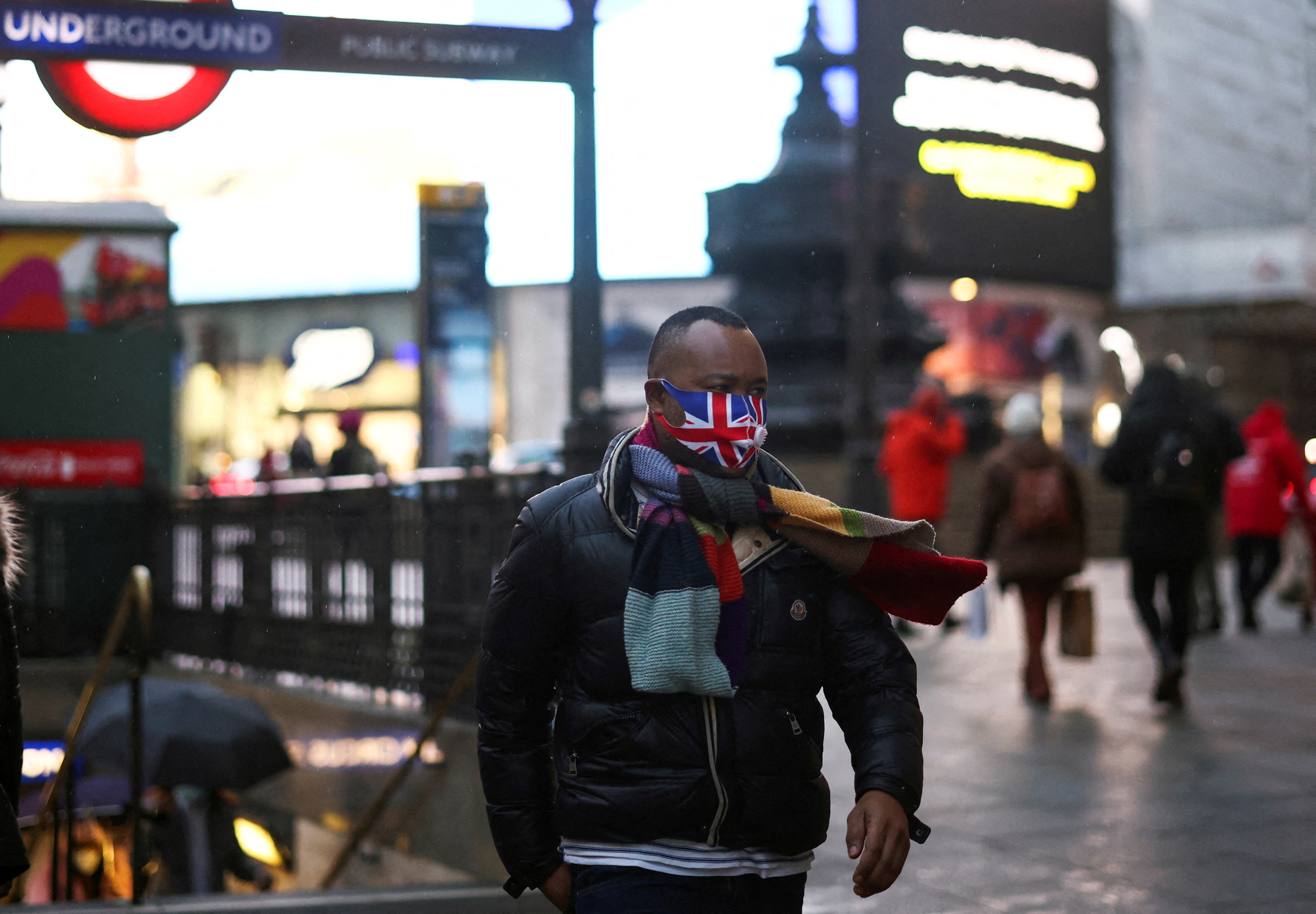 A person wearing a protective face mask walks through Piccadilly Circus, London amid the COVID outbreak