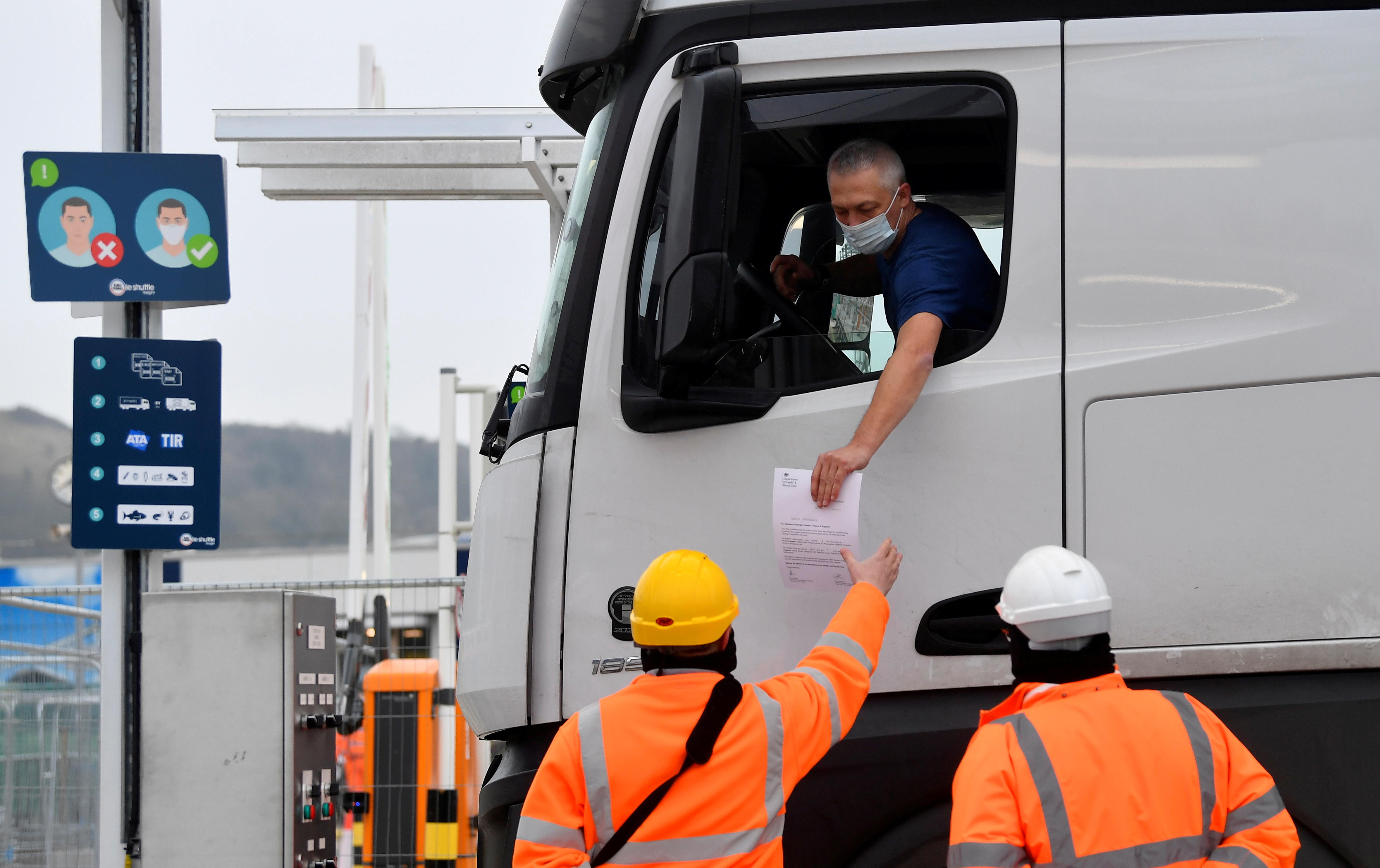 A lorry driver shows documentation to officials for both customs clearance and COVID-19.