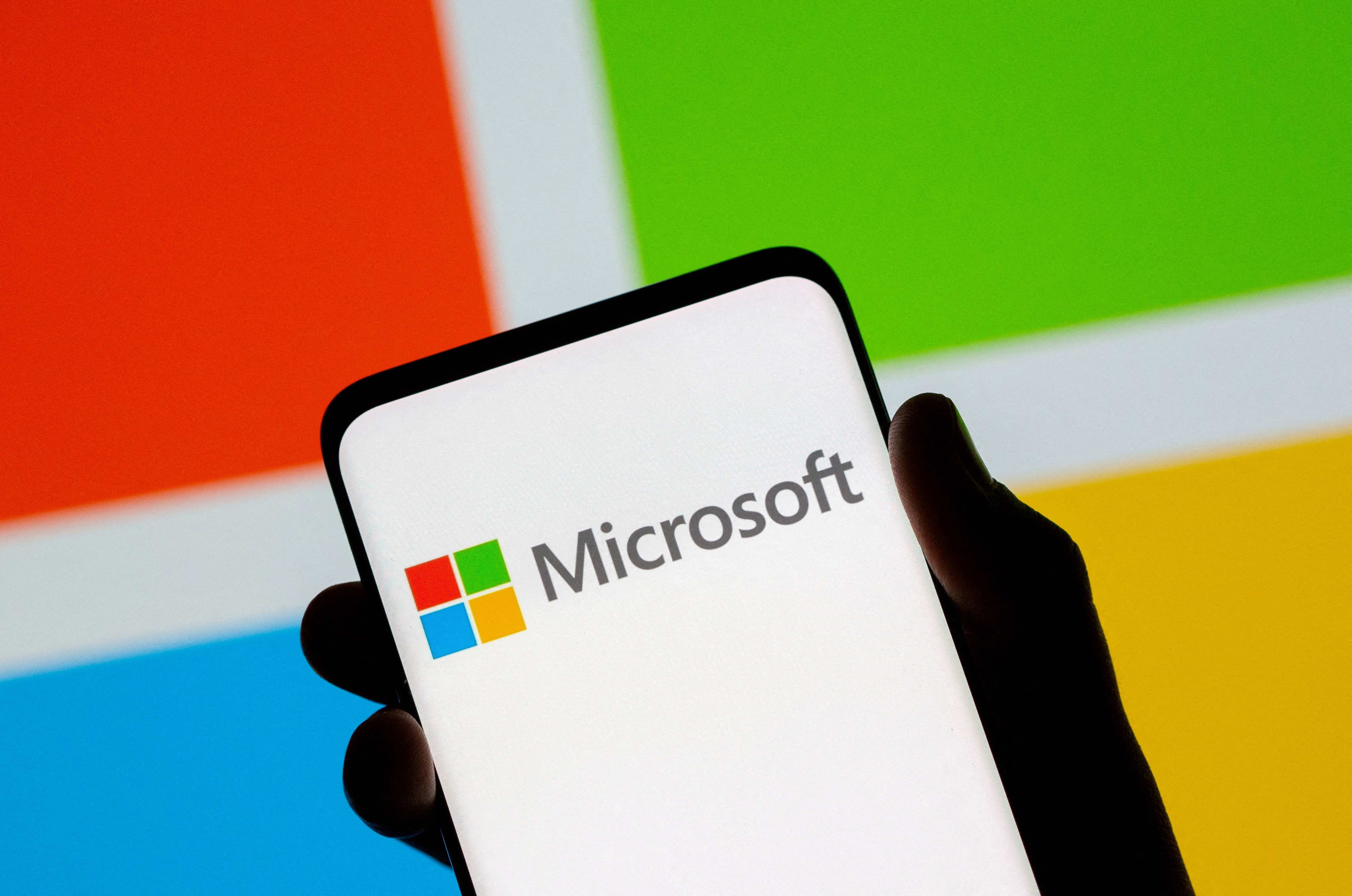 A smartphone is seen in front of the Microsoft logo