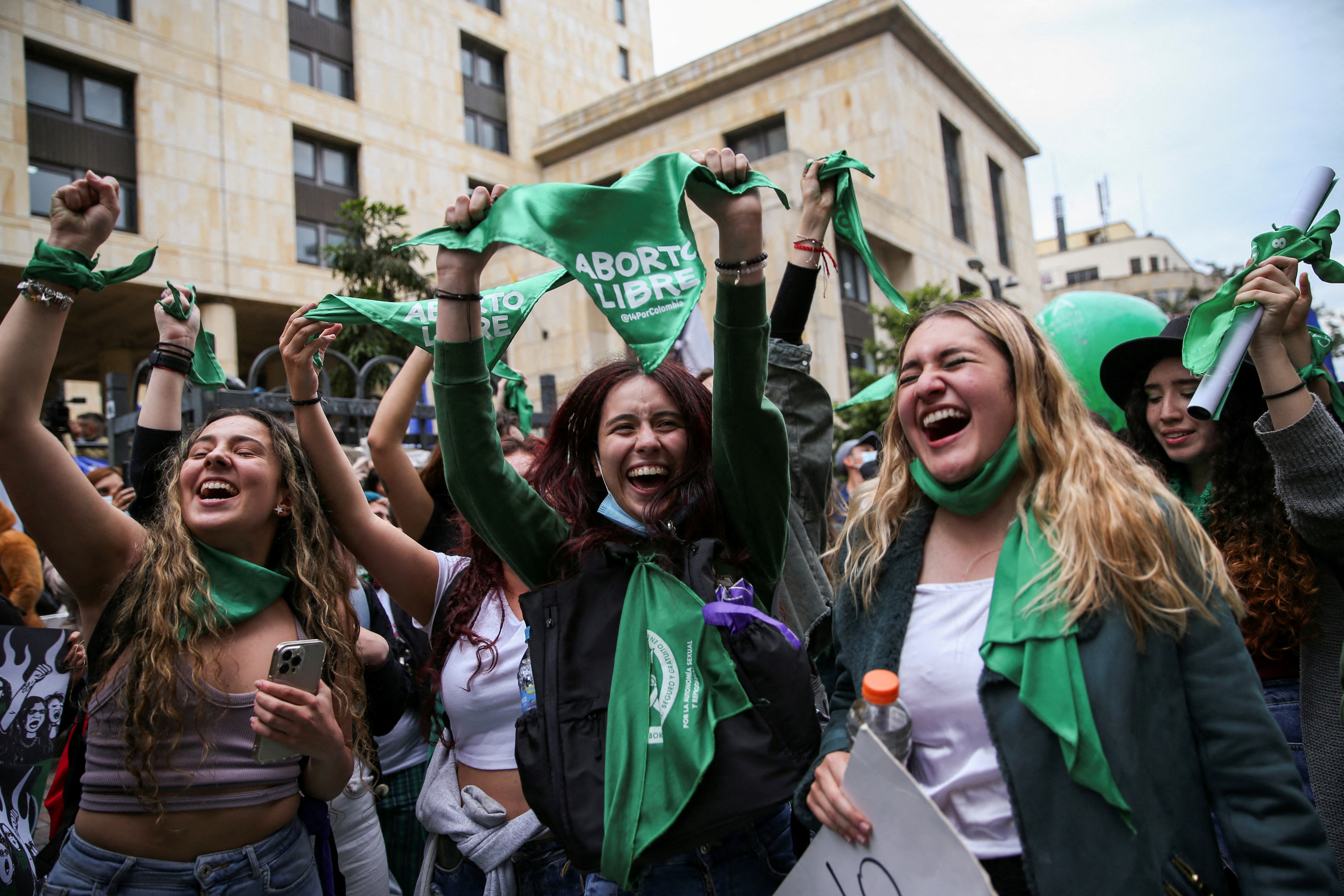 women waving green banners cheer outside the constitutional court in Bogota Colombia