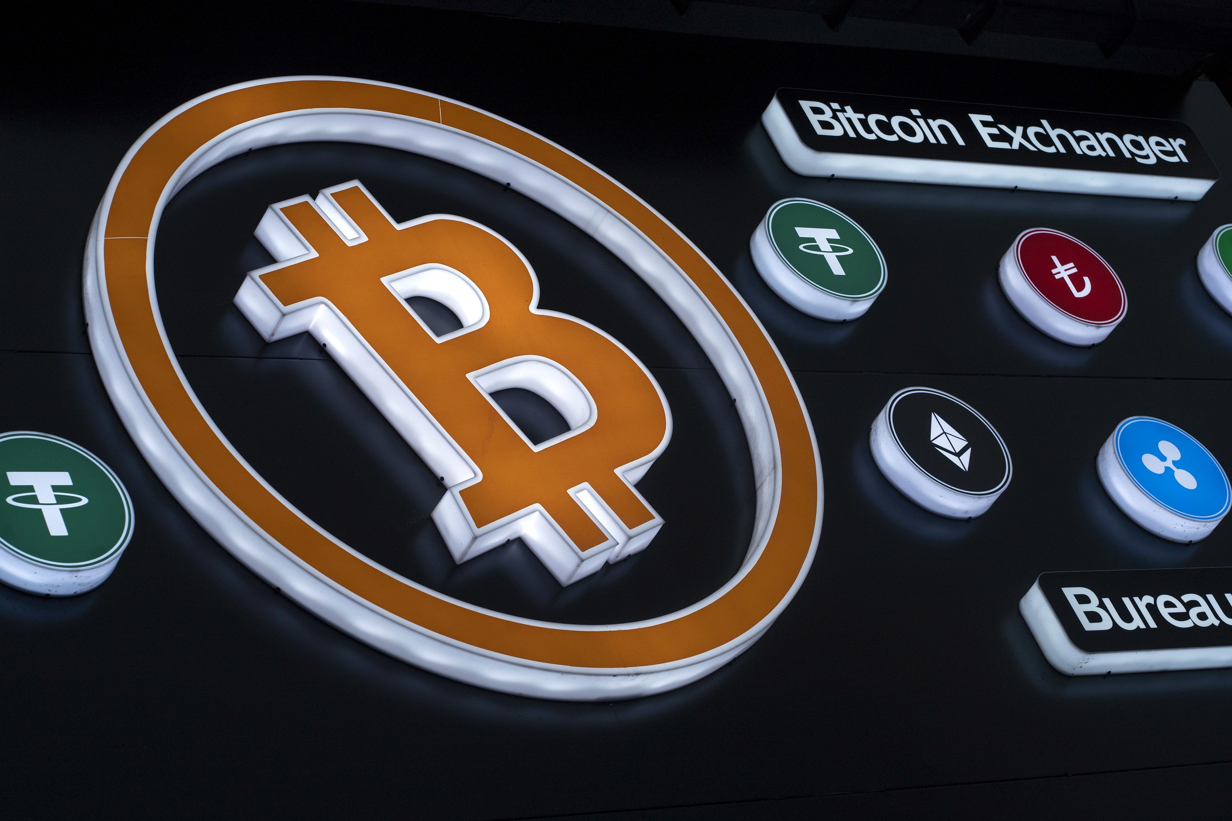 Cryptocurrency logos in the window of an exchange kiosk