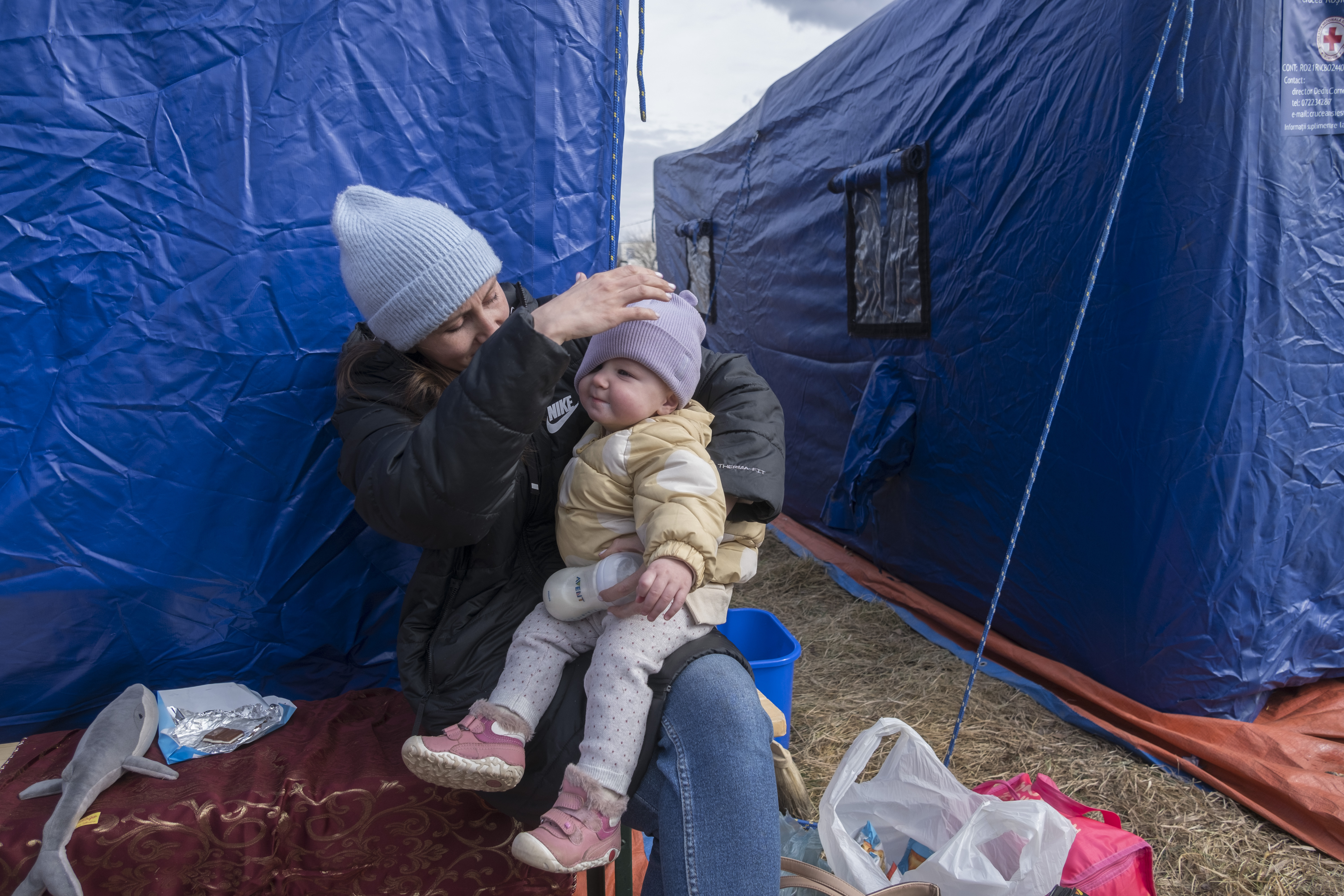 A Ukrainian mother takes a break to feed her baby at the temporary shelter tents nearby the Siret border crossing.