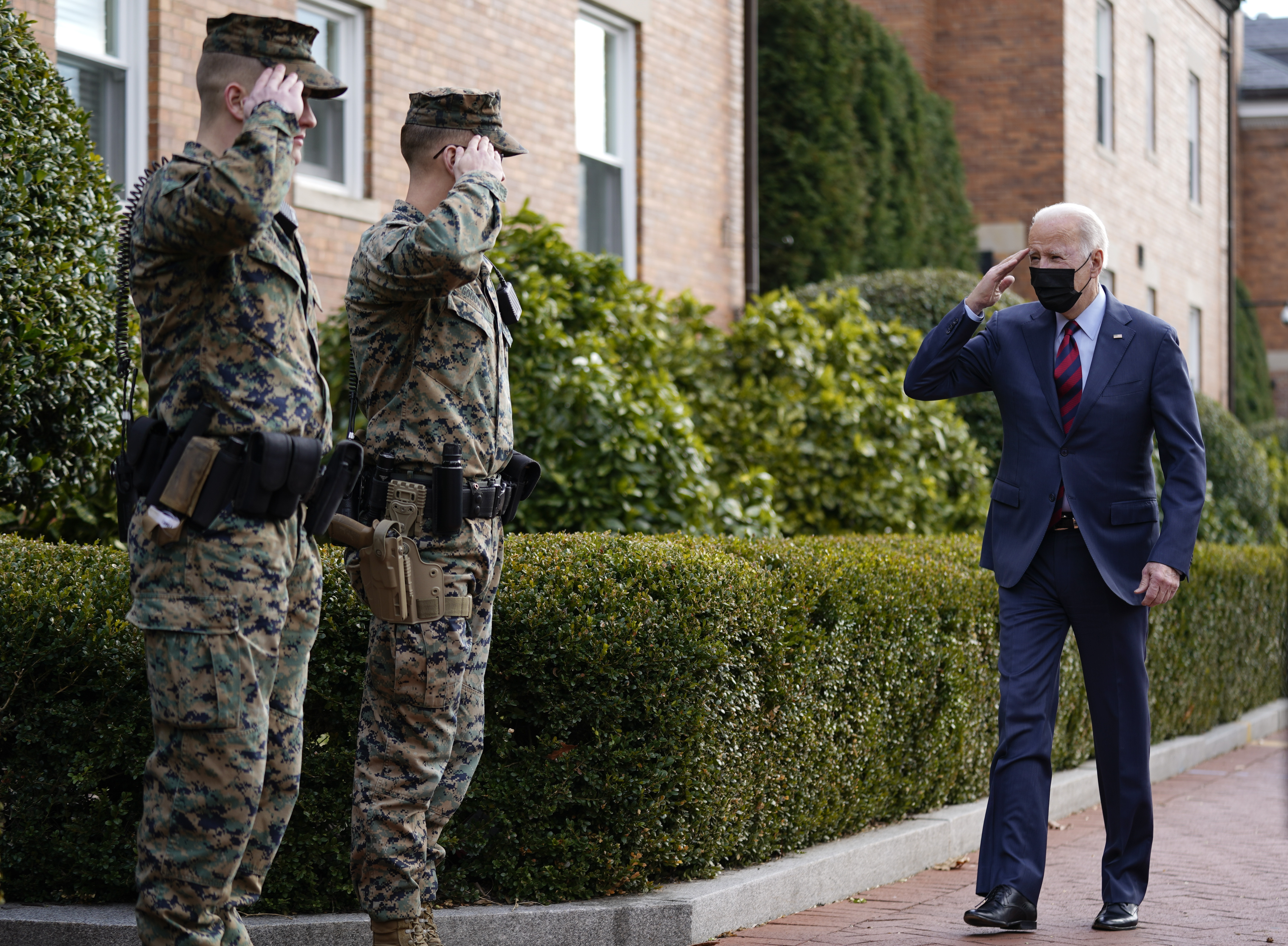 President Joe Biden returns a salute as he walks by the Marine Barracks in Washington, DC