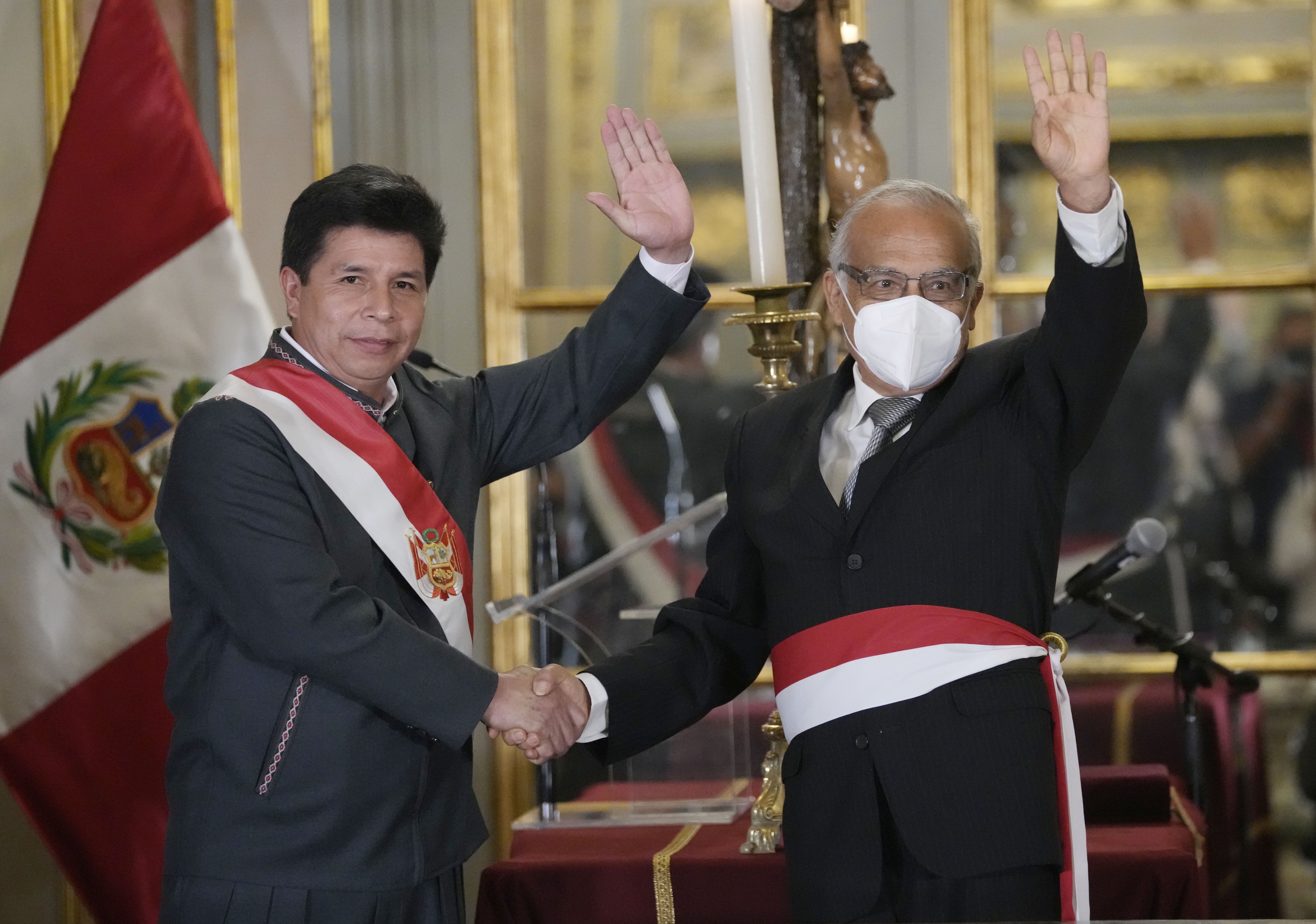 Peru's President Pedro Castillo, left, waves alongside his new Cabinet Chief Anibal Torres, during the swearing-in of Castillos´s new Cabinet, at the government palace in Lima, Peru, Tuesday, Feb. 8, 2022