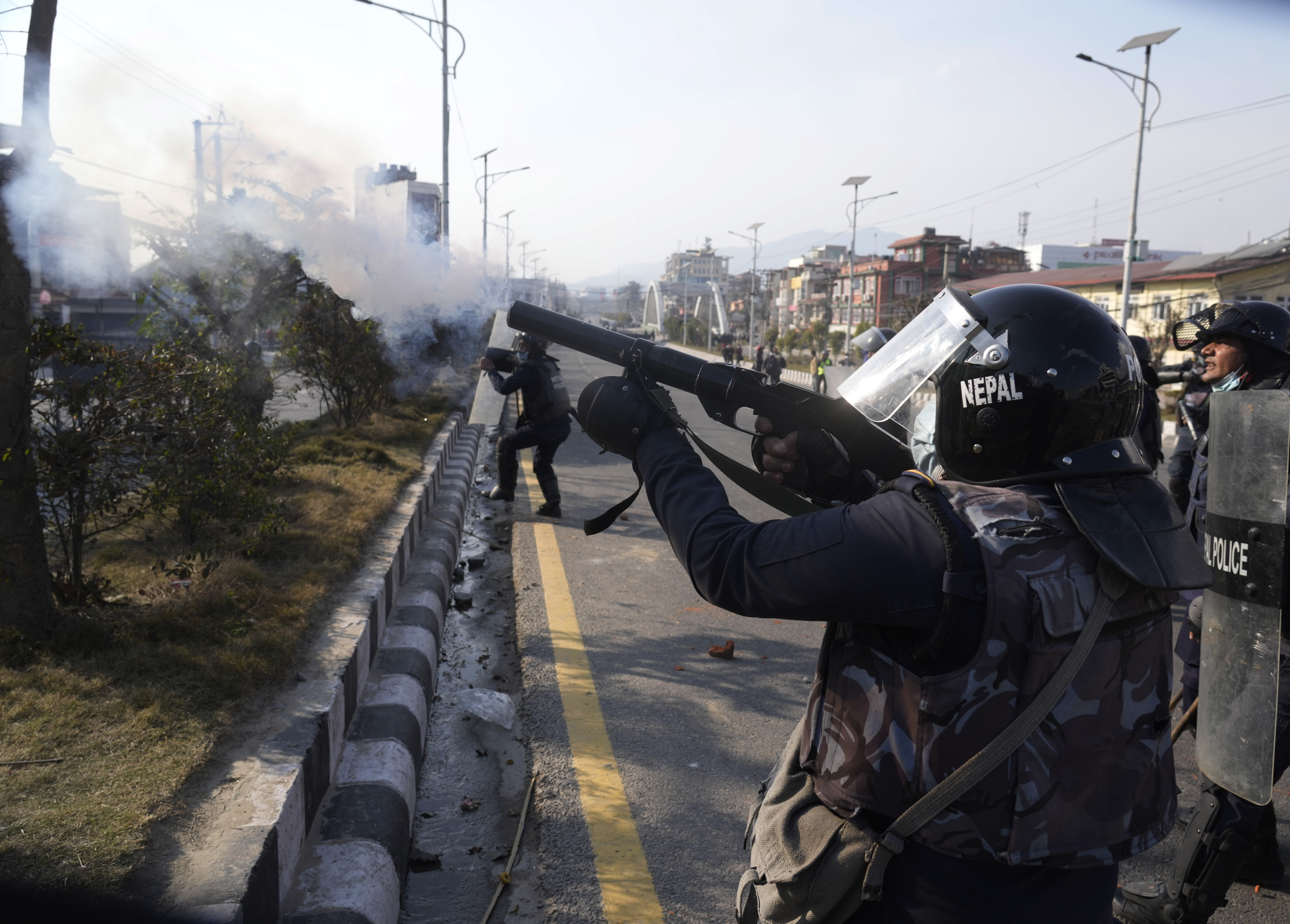 A Nepalese policeman fires tear gas at protesters in the capital Kathmandu