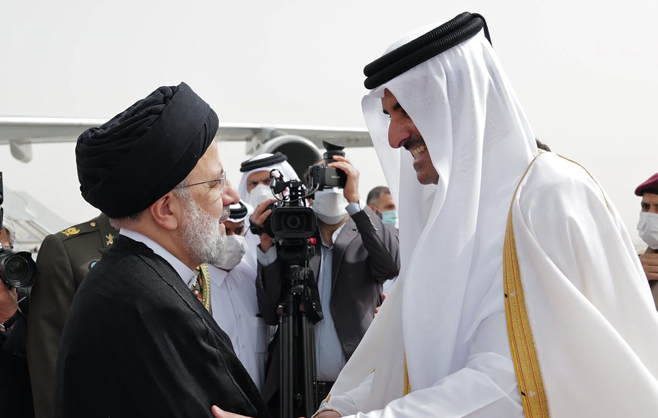 In this photo made available by Qatar News Agency, QNA, President Ebrahim Raisi, left, is welcomed by Qatari Emir Tamim bin Hamad Al Thani,