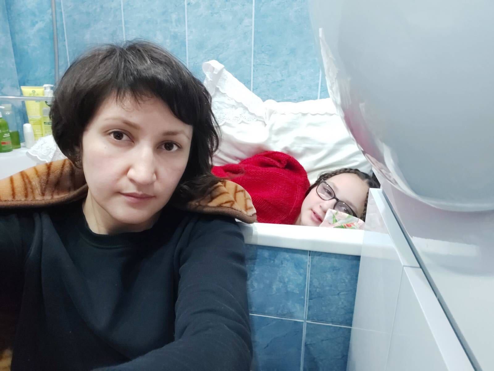 Since Saturday, Zakhida Adylova, a Ukrainian woman with short dark hair is seen sitting on the floor of her blue tiled bathroom while her 11-year-old daughter Samira lies in the bathtub