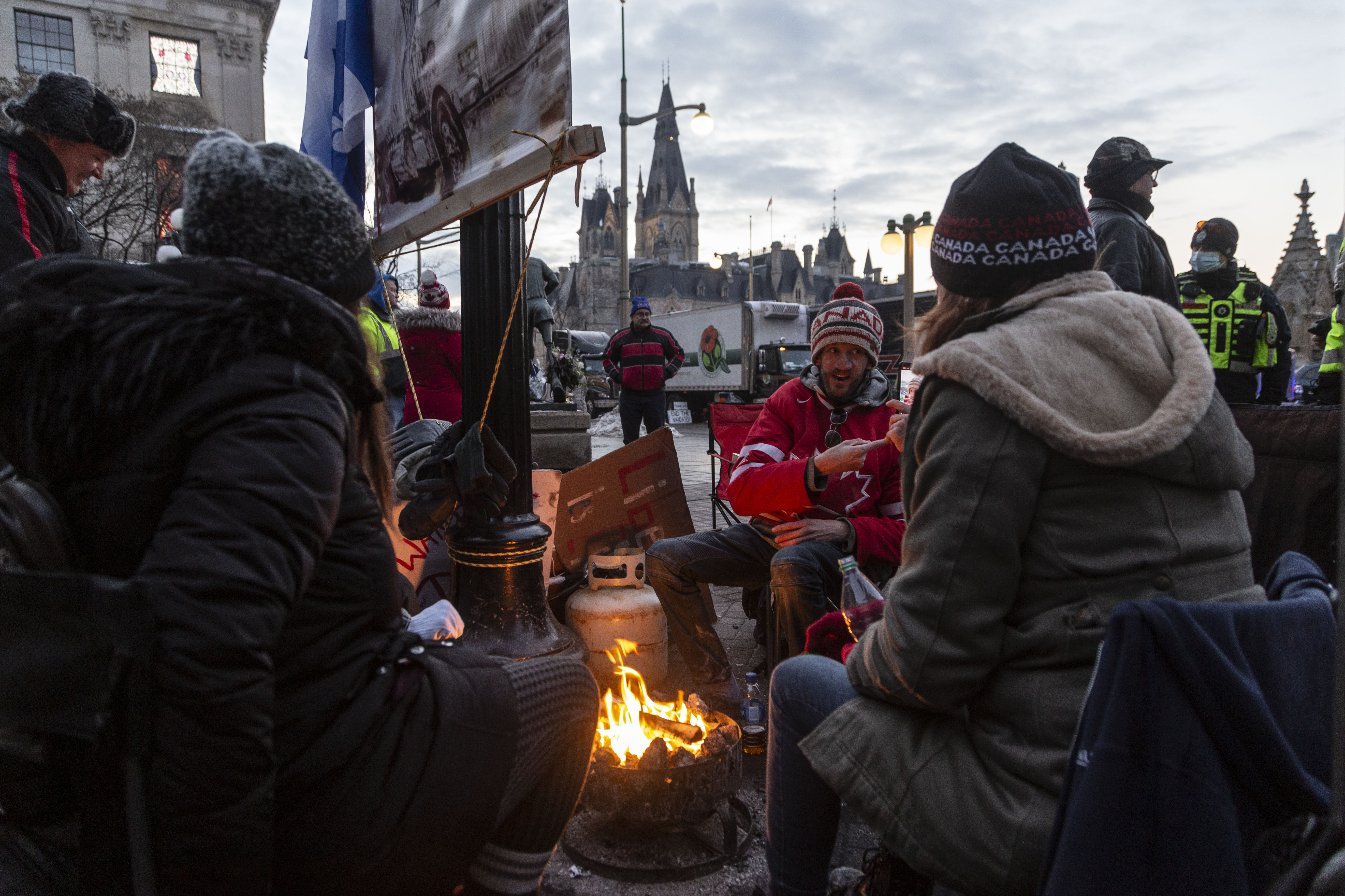 Protesters warm themselves by a charcoal fire on the sidewalk of Wellington street.