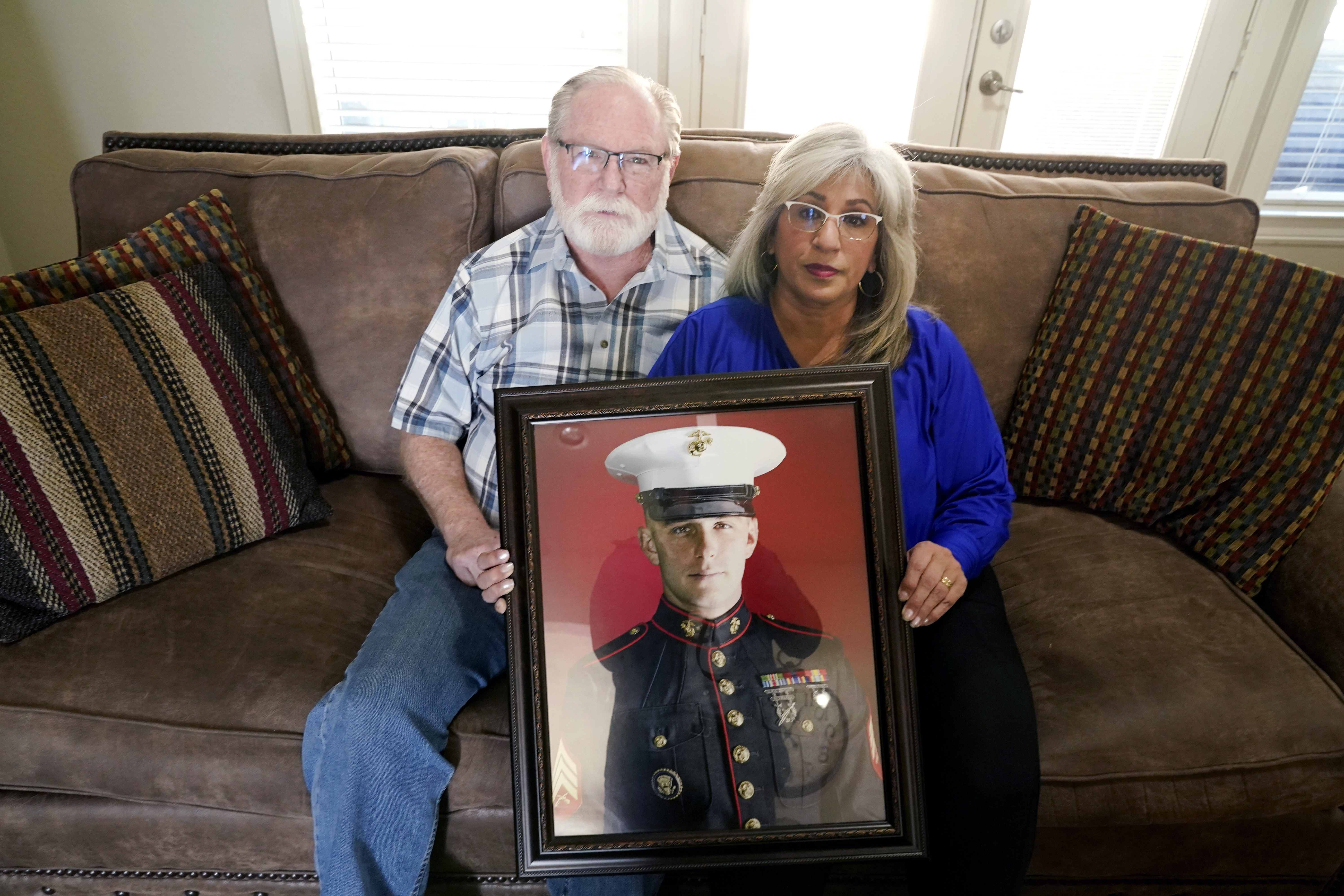 Joey and Paula Reed pose for a photo with a portrait of their son Marine veteran and Russian prisoner Trevor Reed at their home in Fort Worth, Texas