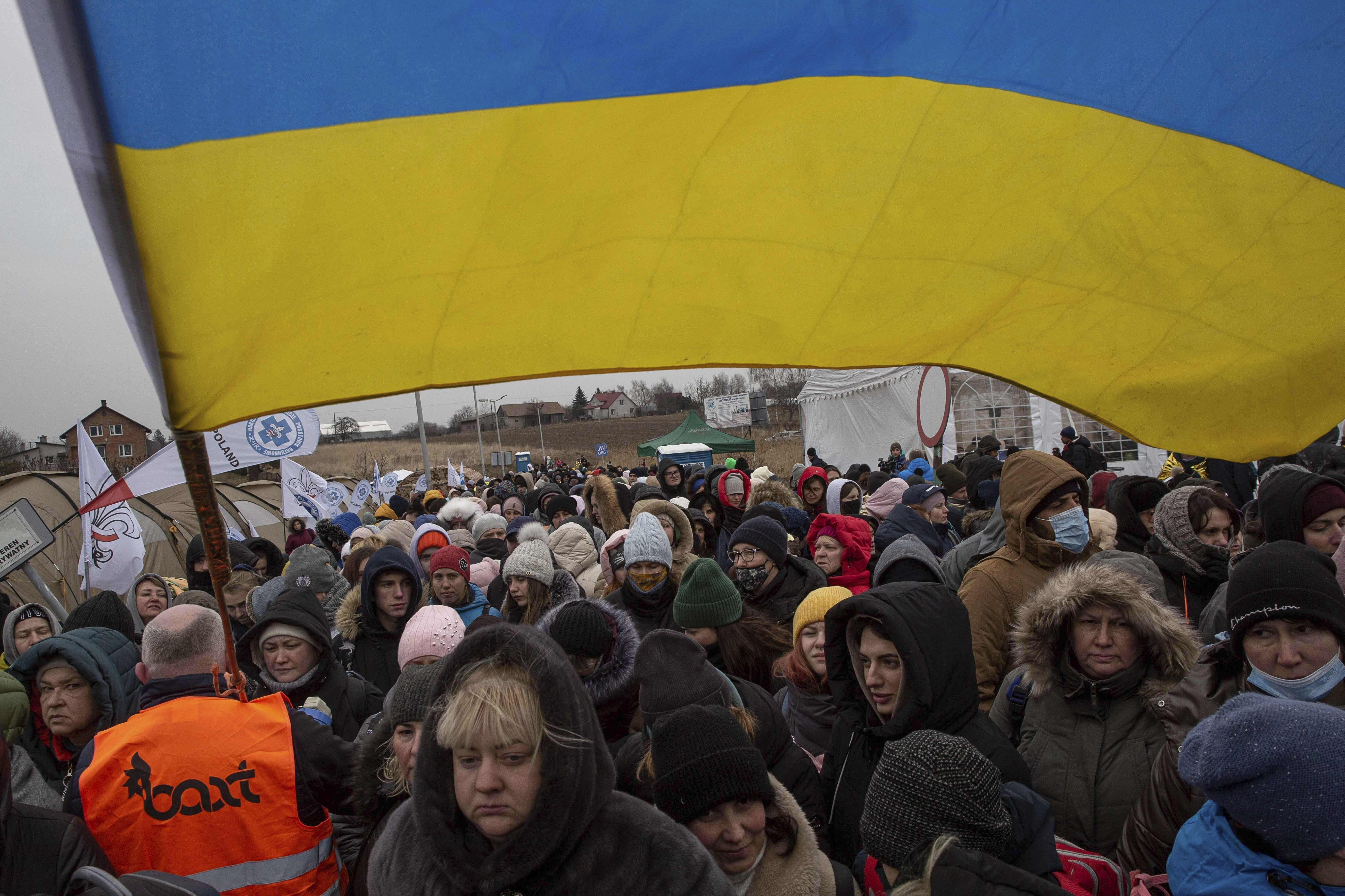 A Ukrainian volunteer Oleksandr Osetynskyi, 44 holds a Ukrainian flag and directs refugees after fleeing from Ukraine and arriving at the border crossing in Medyka, Poland