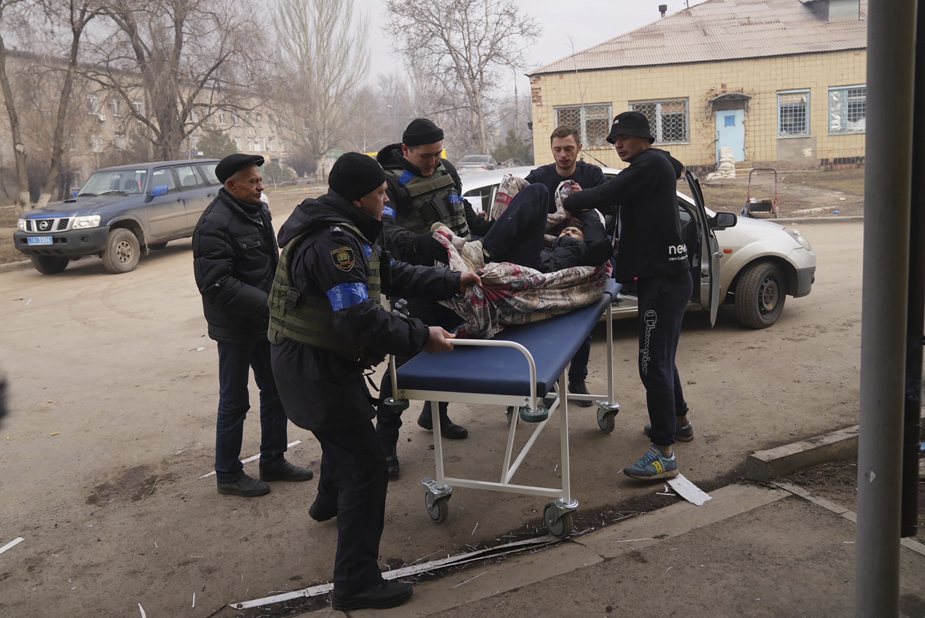 Ukrainian servicemen and volunteers carry a man injured 