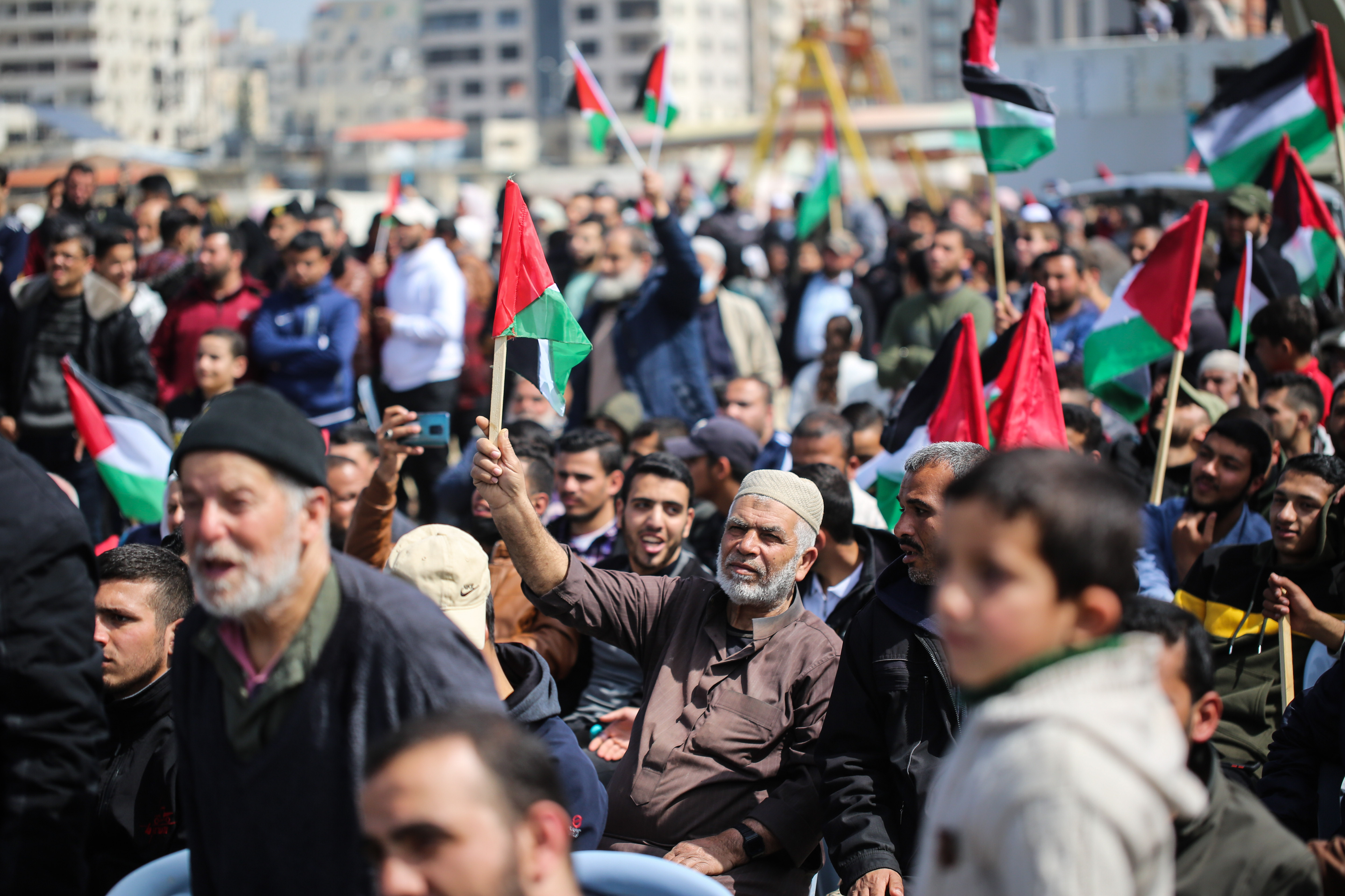 A man holds the Palestinian flag among the masses.