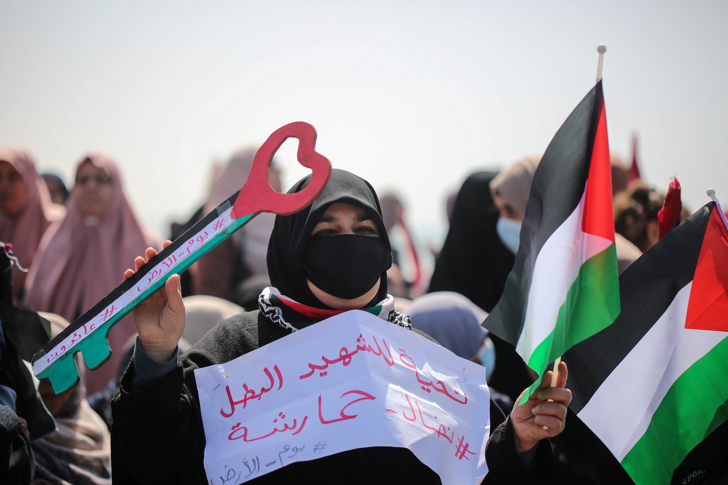 A Palestinain woman holds the flag and the return key.