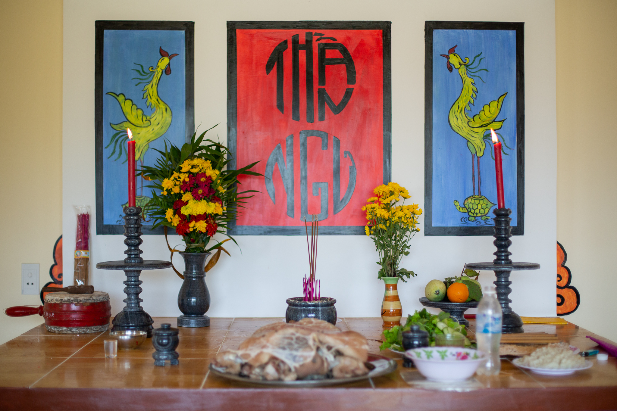 A photo of flowers, meat, fruit and rice wine rest on al alter in one of Tam Hai’s whale temples.