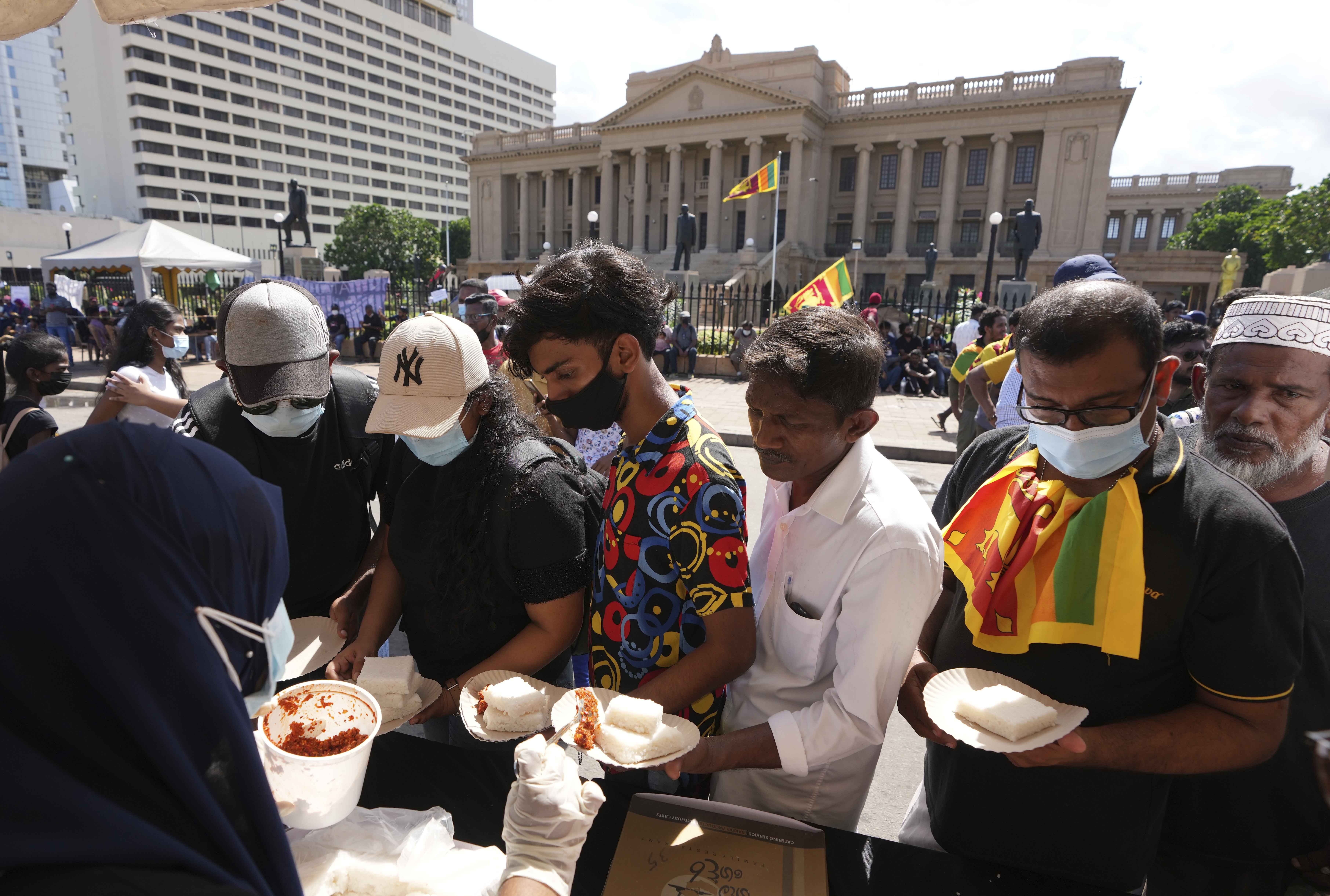 Sri Lankans receive traditional delicacies as they mark the dawn of Sinhalese and Tamil new year during an anti-government protest near the president’s office in Colombo