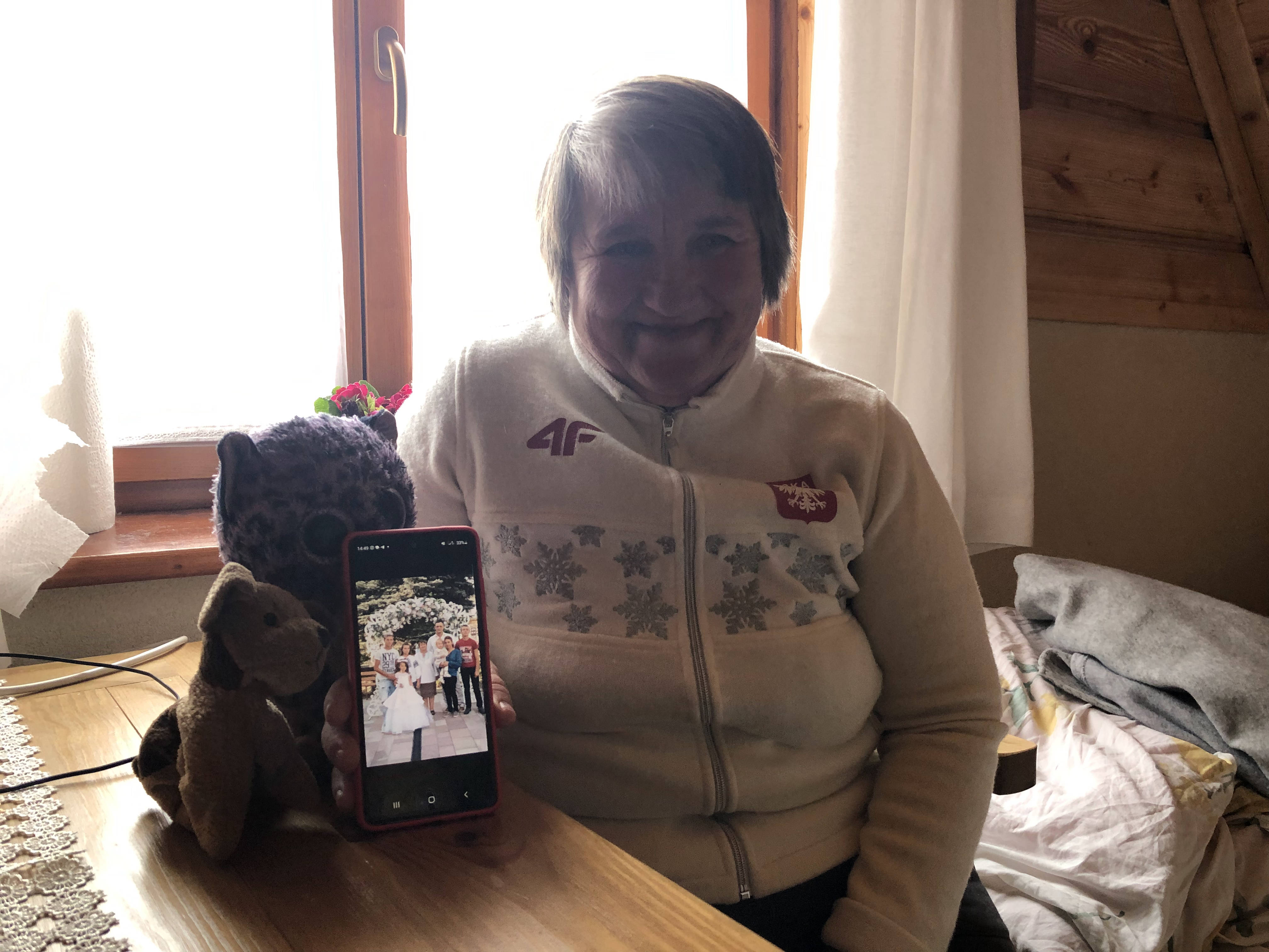 A photo of Olha Sydor and her belongings in her room, holding up family portrait.