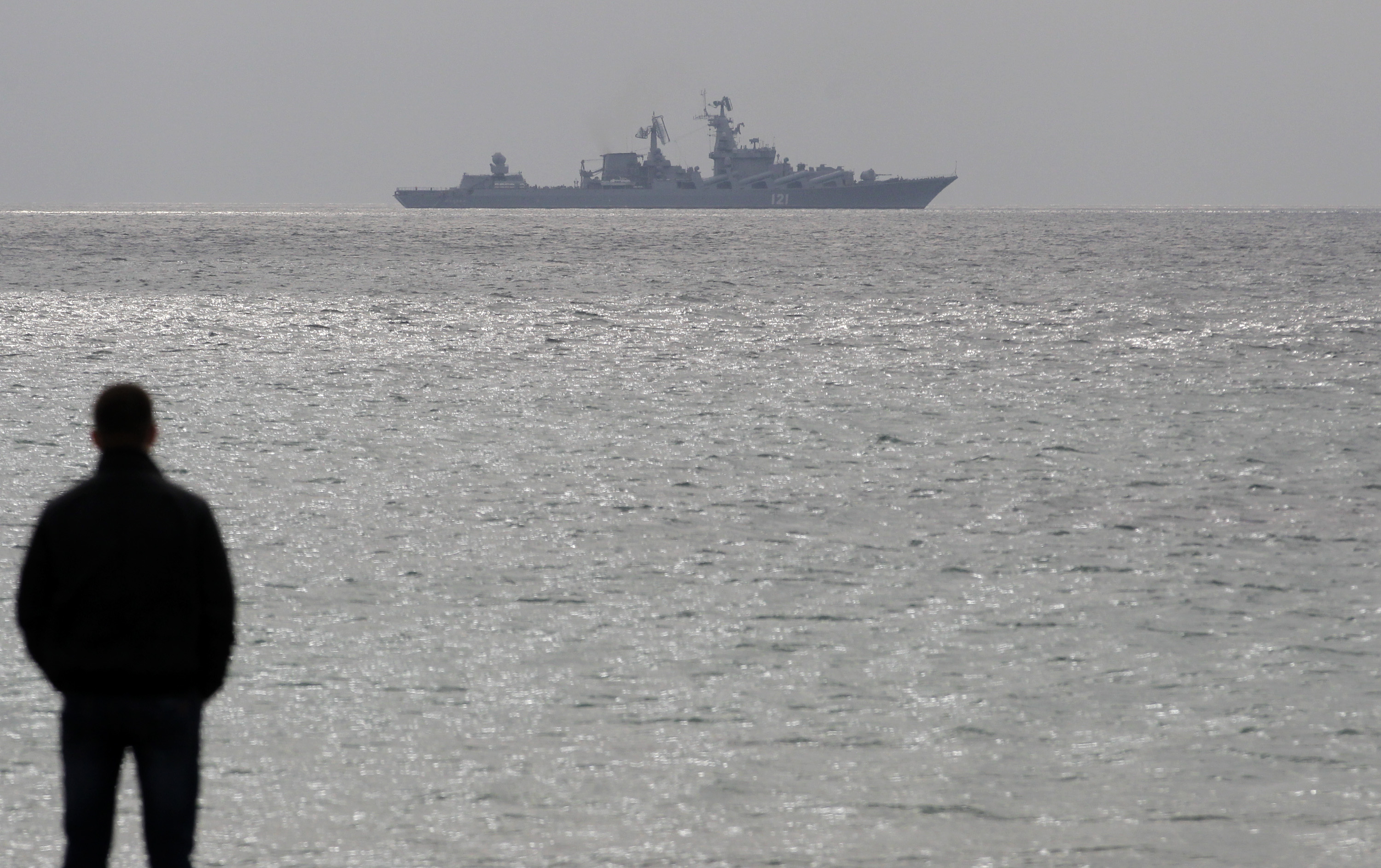 A man looks out to sea as the Russian warship "Moskva" ("Moscow") sails at a Black Sea shore outside the town of Myrnyi, western Crimea, Ukraine