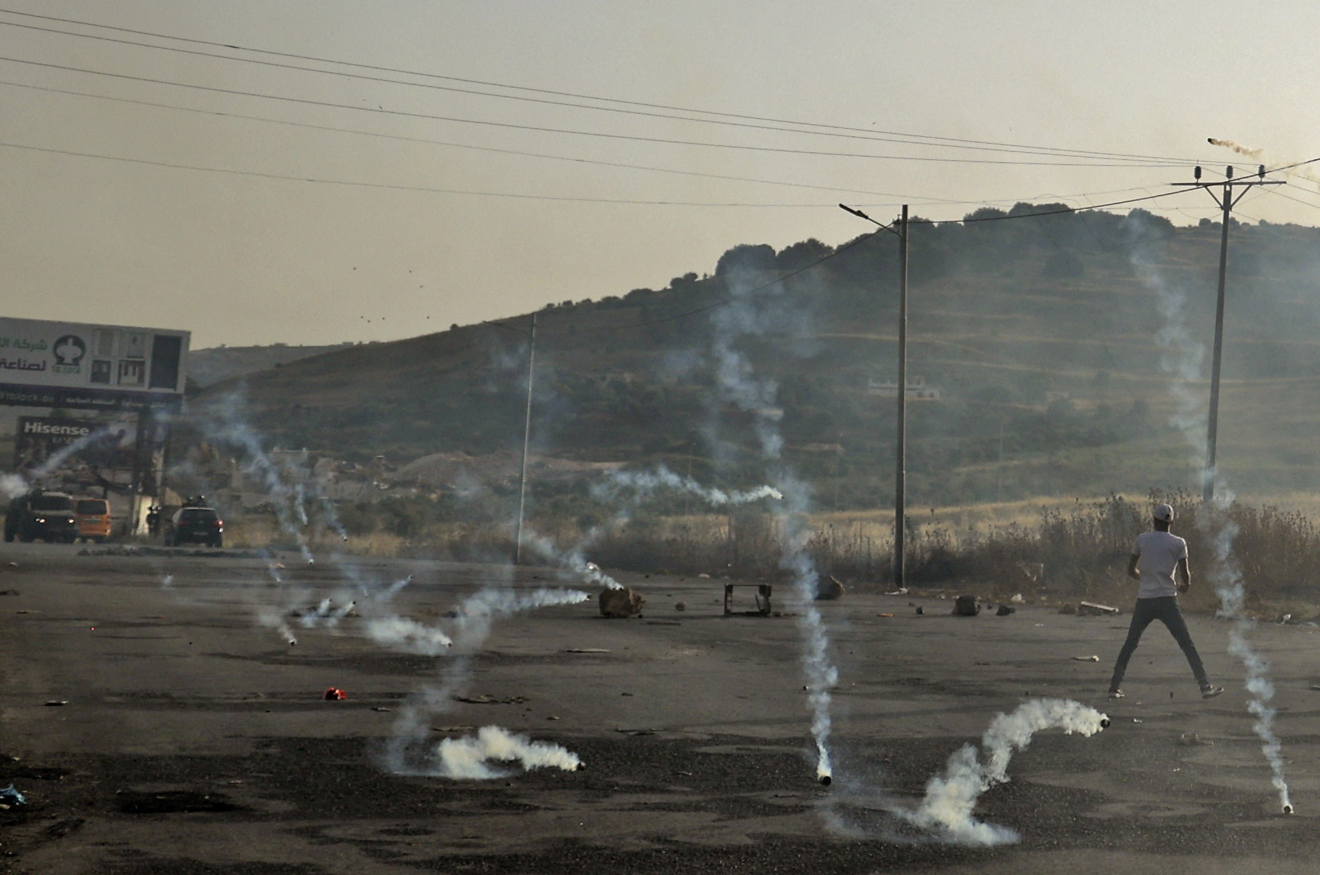 Tear gas canisters fired by Israeli forces fall amidst Palestinian protesters during clashes following a demonstration to denounce the annual nationalist "flag march" through Jerusalem, at the Israeli-controlled Hawara checkpoint near Nablus in the occupied West Bank