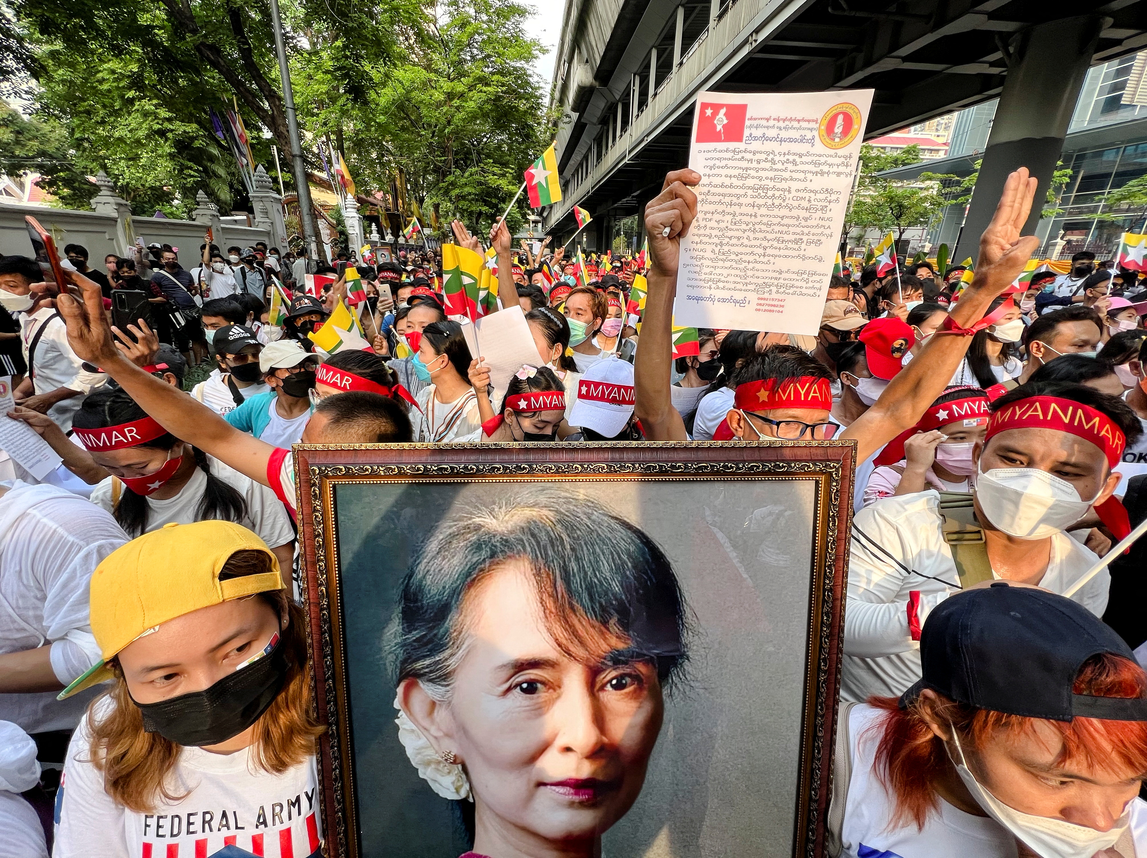 Myanmar migrant workers demonstrate against the military coup carrying pictures of Aung San Suu Kyi and wearing red bandanas as they march in Bangkok