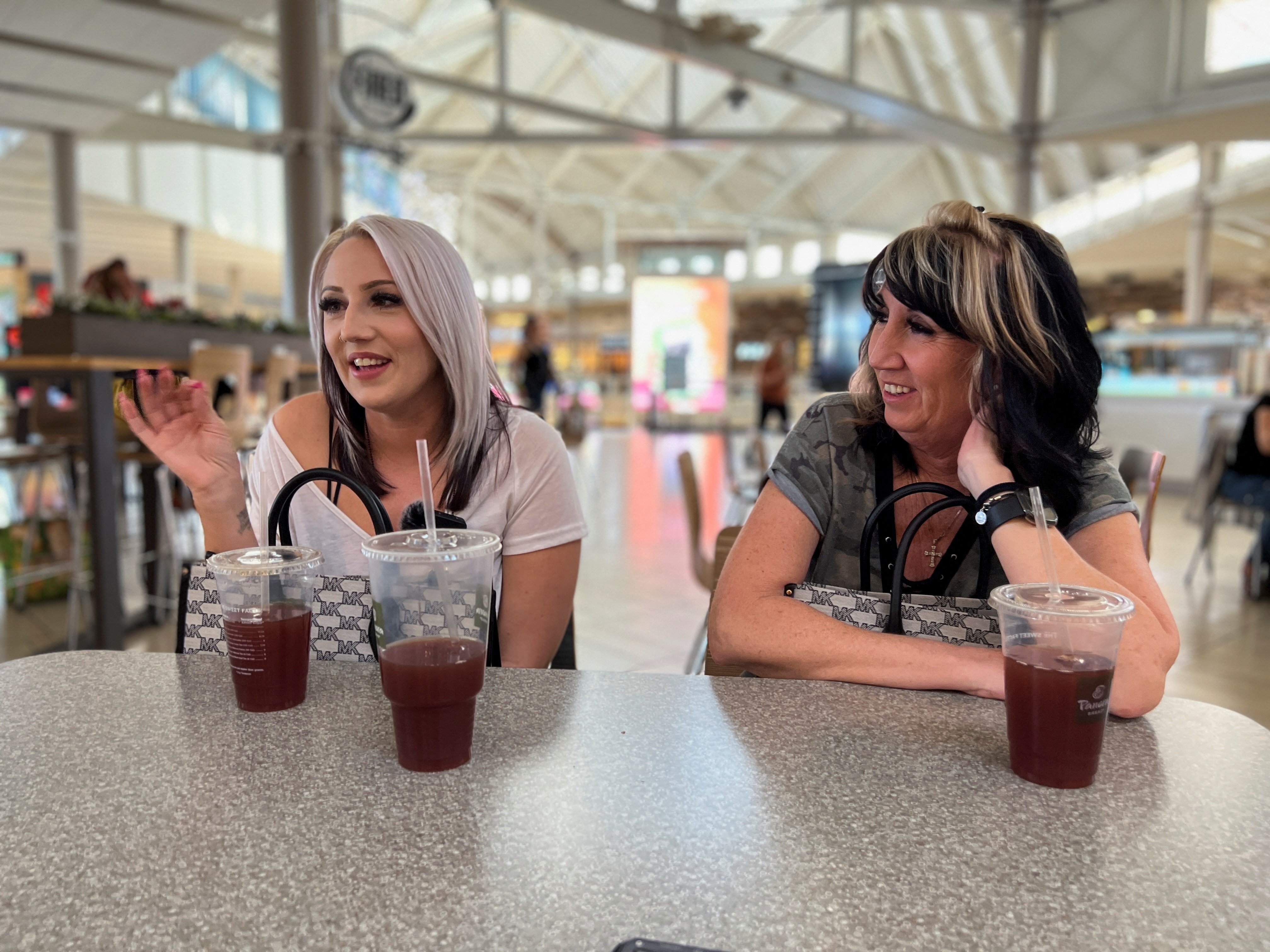 Sherica Bailey speaks at a food court table while her mother looks on