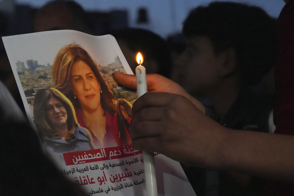 Palestinian holds a candle and a picture of slain Shireen Abu Akleh