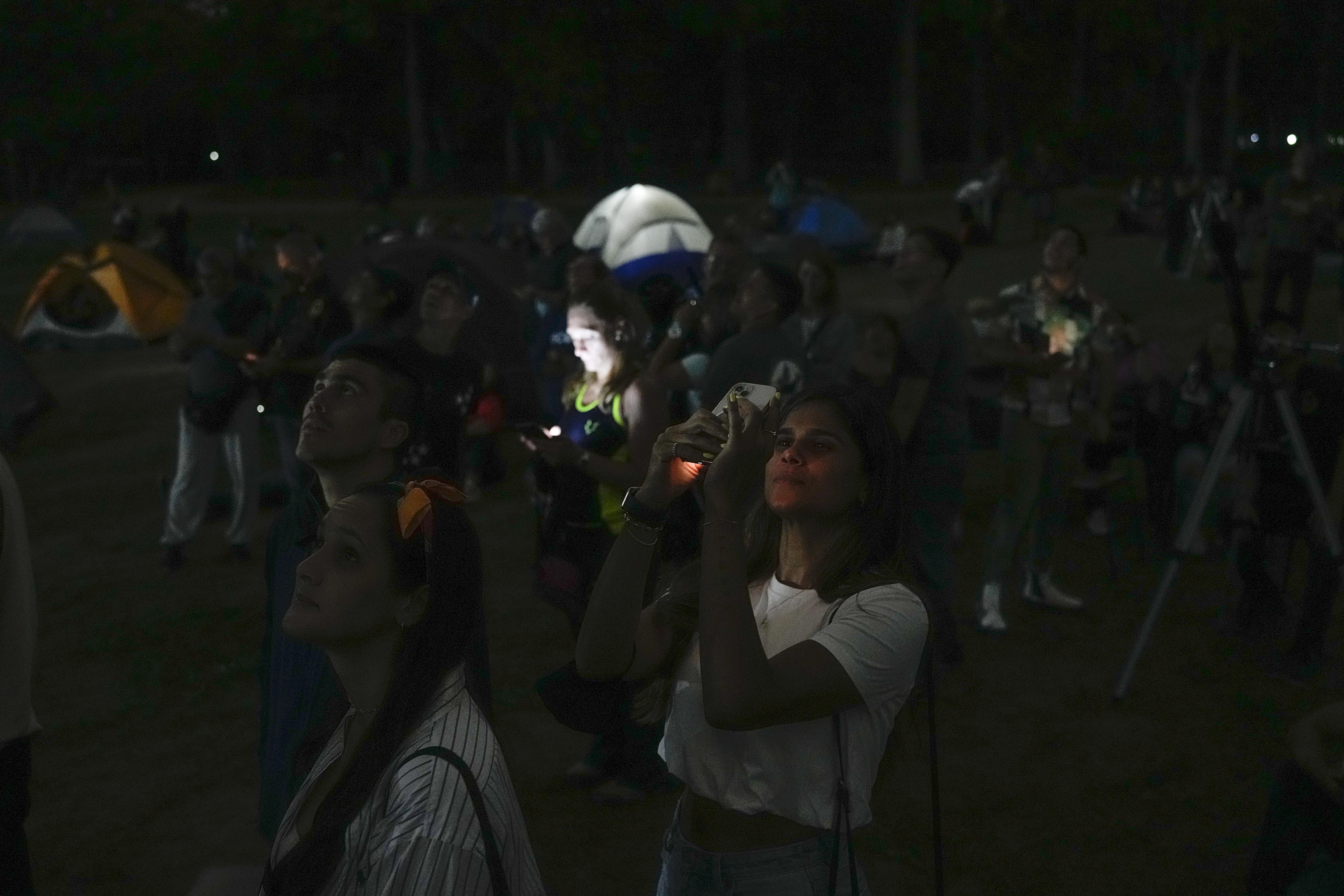A woman takes a photo of the moon with her cellphone during the first blood moon of the year, in Caracas, Venezuela