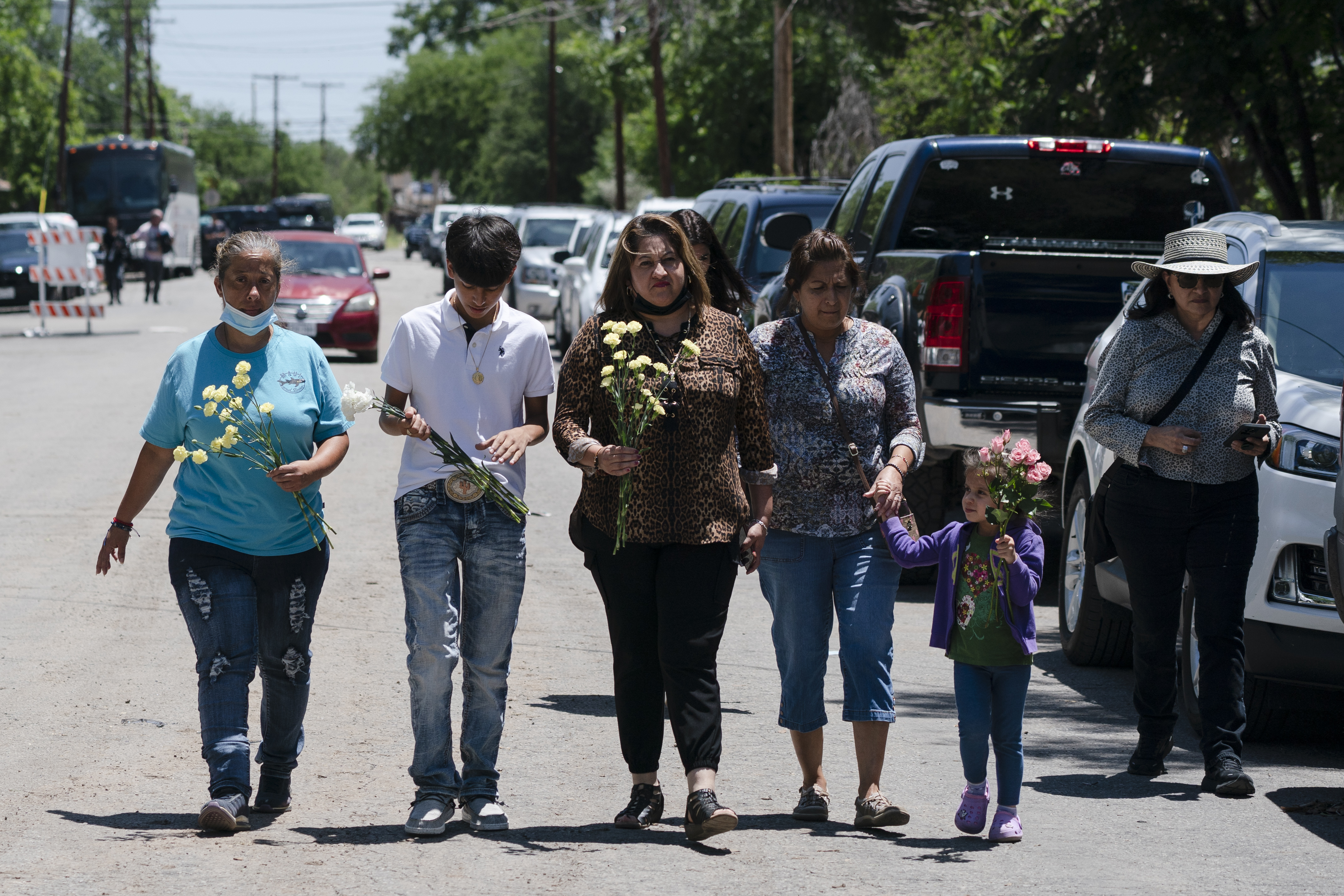 People walk with flowers to honour the victims in Tuesday’s shooting