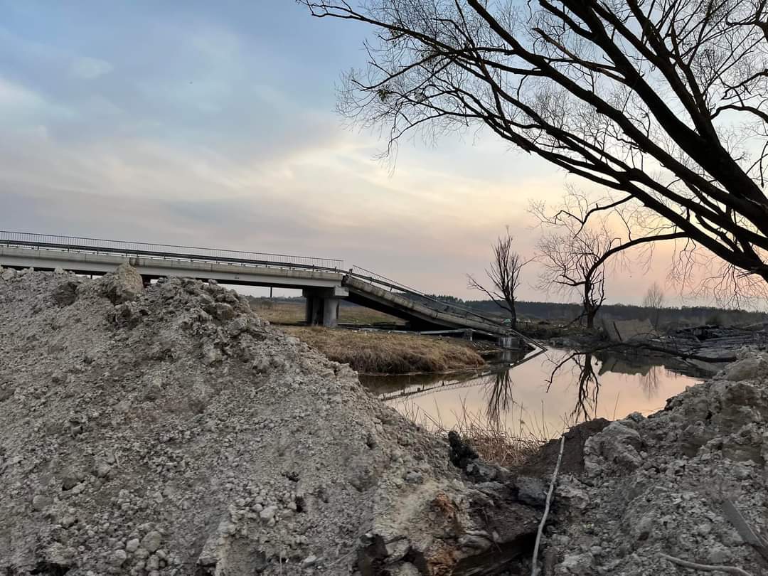 A photo of a destroyed bridge next to a river.