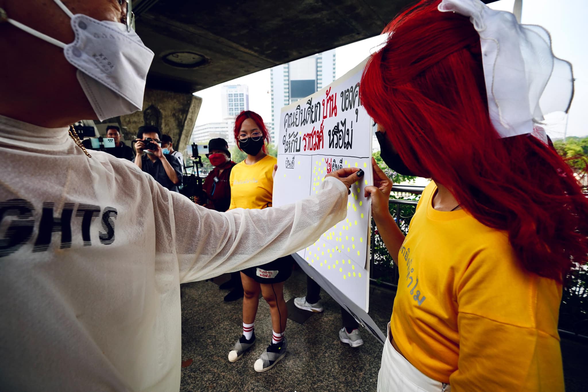Thaluwang runs a questionnaire on the street in Bangkok, asking passers-by to show their opinion