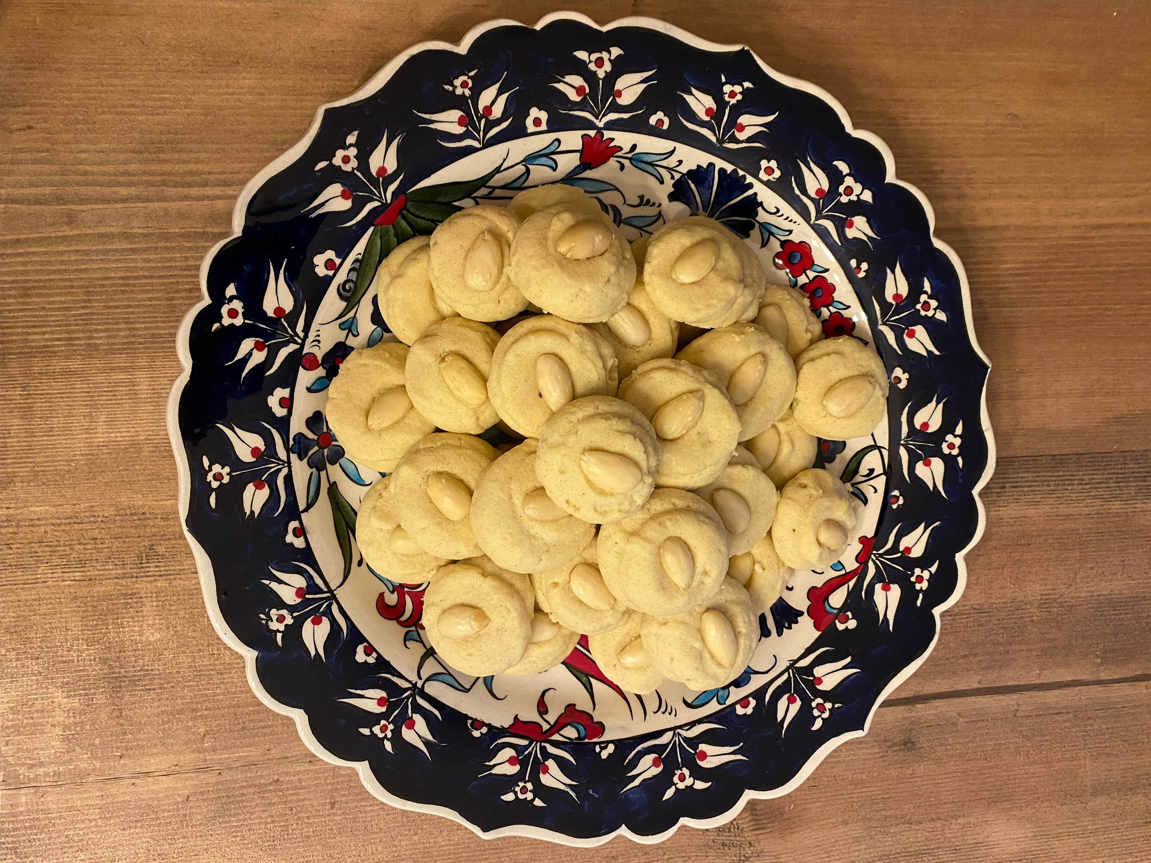 A bowl of ghraiba cookies sits on a wooden table top